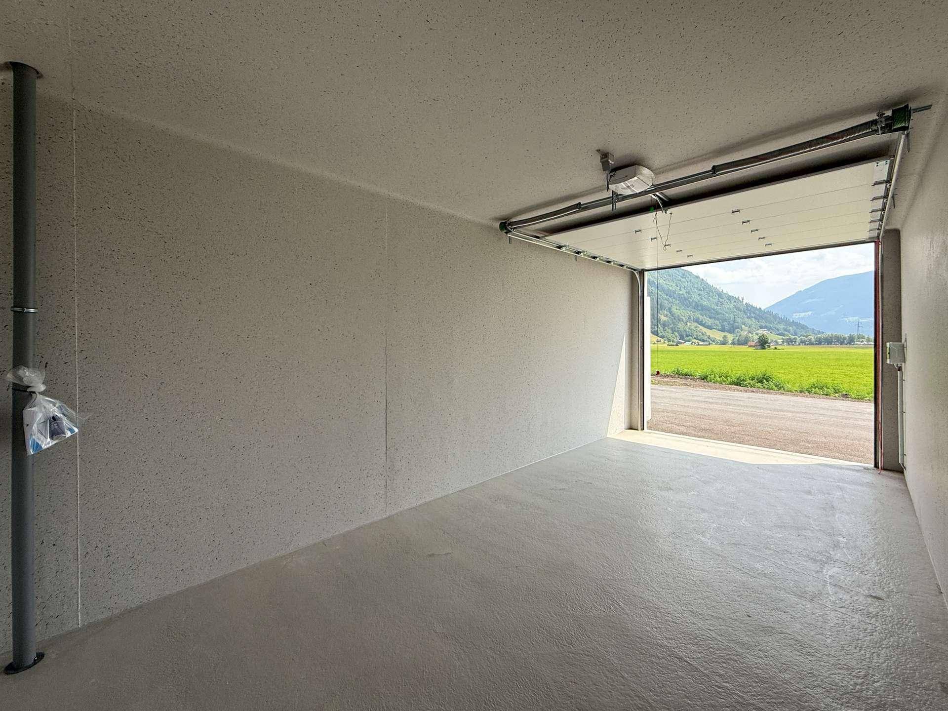 Helle Garagenbox mit Betonboden und weitem Blick auf die umliegende Landschaft durch das Tor.