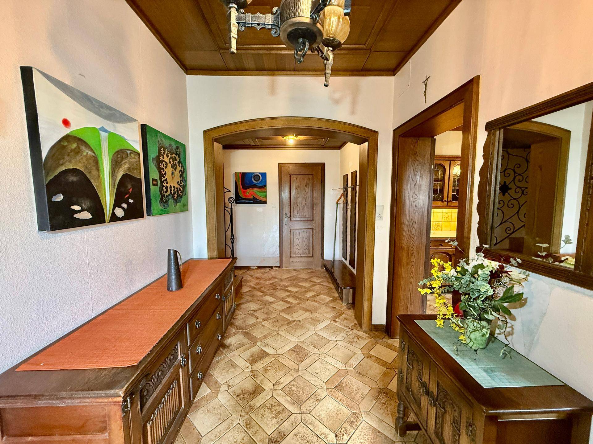 Geräumiger Eingangsbereich mit Holztäfelung an der Decke und gemusterten Fliesenboden.