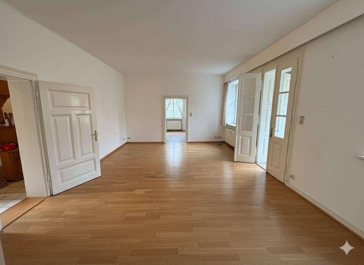 Heller, leerer Wohnraum mit hellem Parkettboden und weißen Türen.