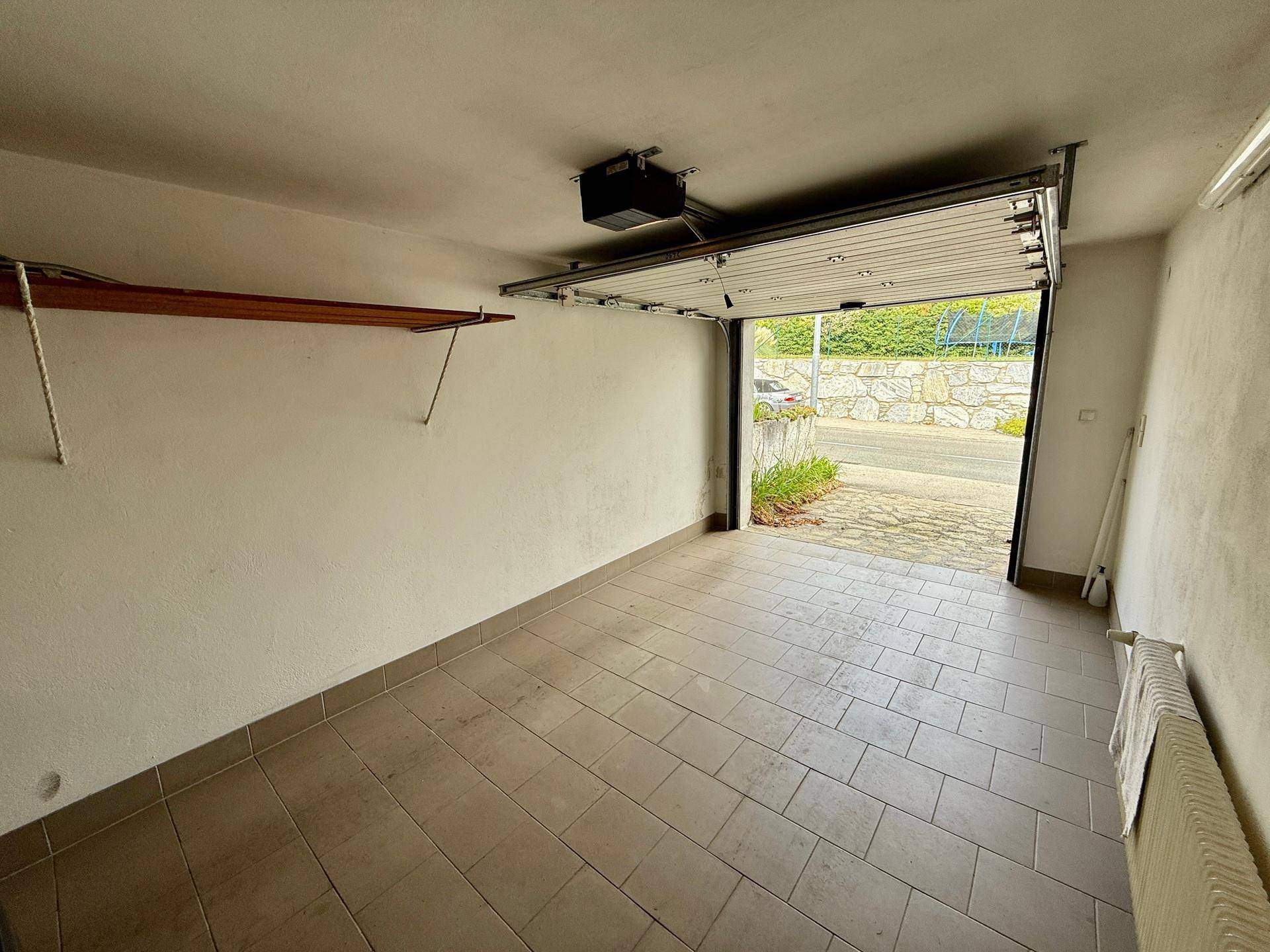 Geräumige Garage mit Fliesenboden und automatischem Garagentor.