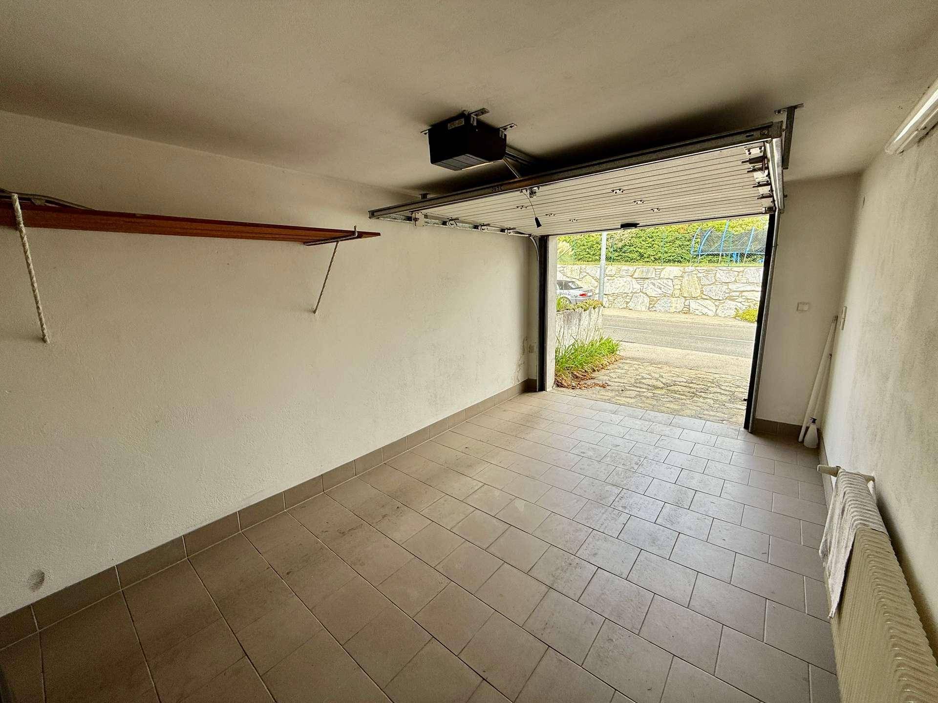 Geräumige Garage mit Fliesenboden und automatischem Garagentor.