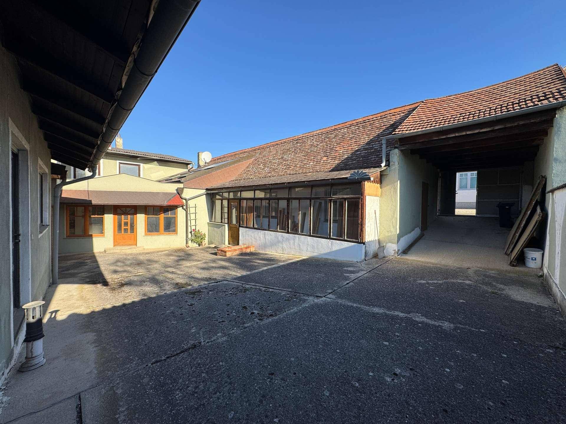Innenhof mit gepflasterter Fläche und Zugang zu verschiedenen Gebäudeteilen.