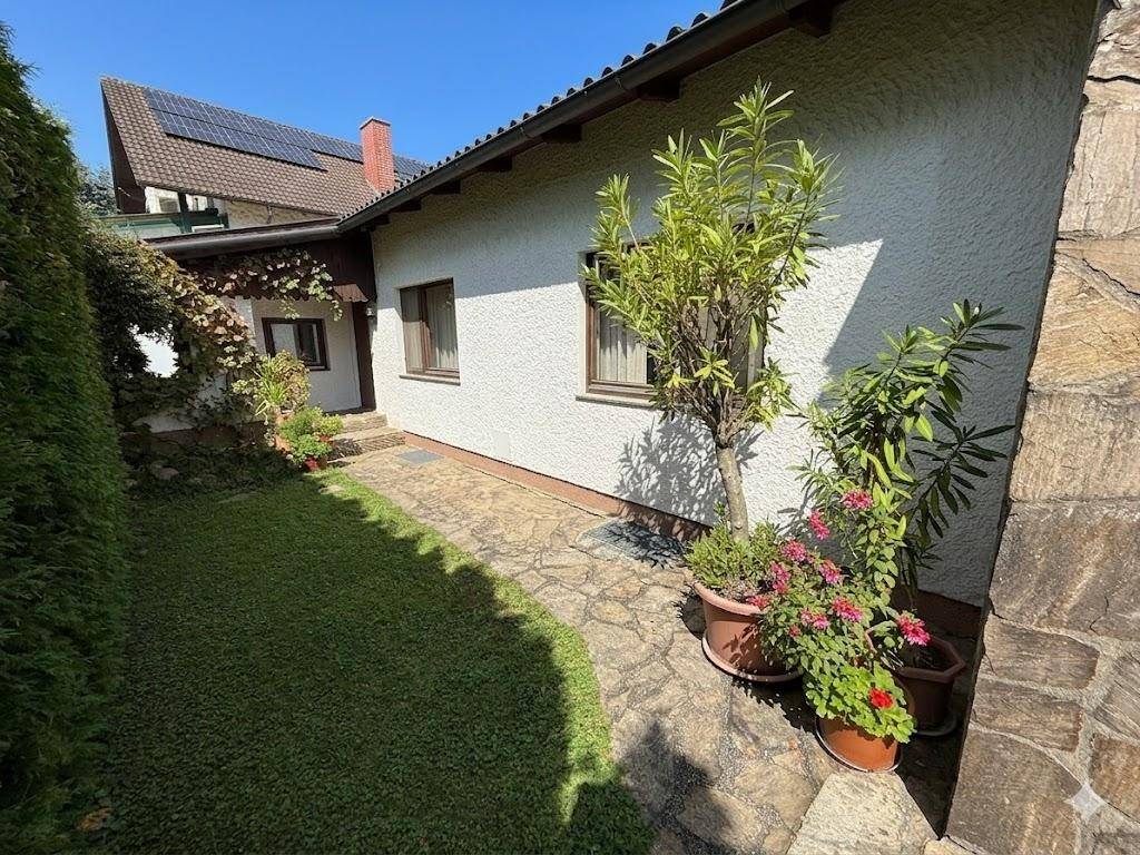 Seitlicher Gartenbereich mit gepflastertem Weg, Blumen und üppiger Bepflanzung.
