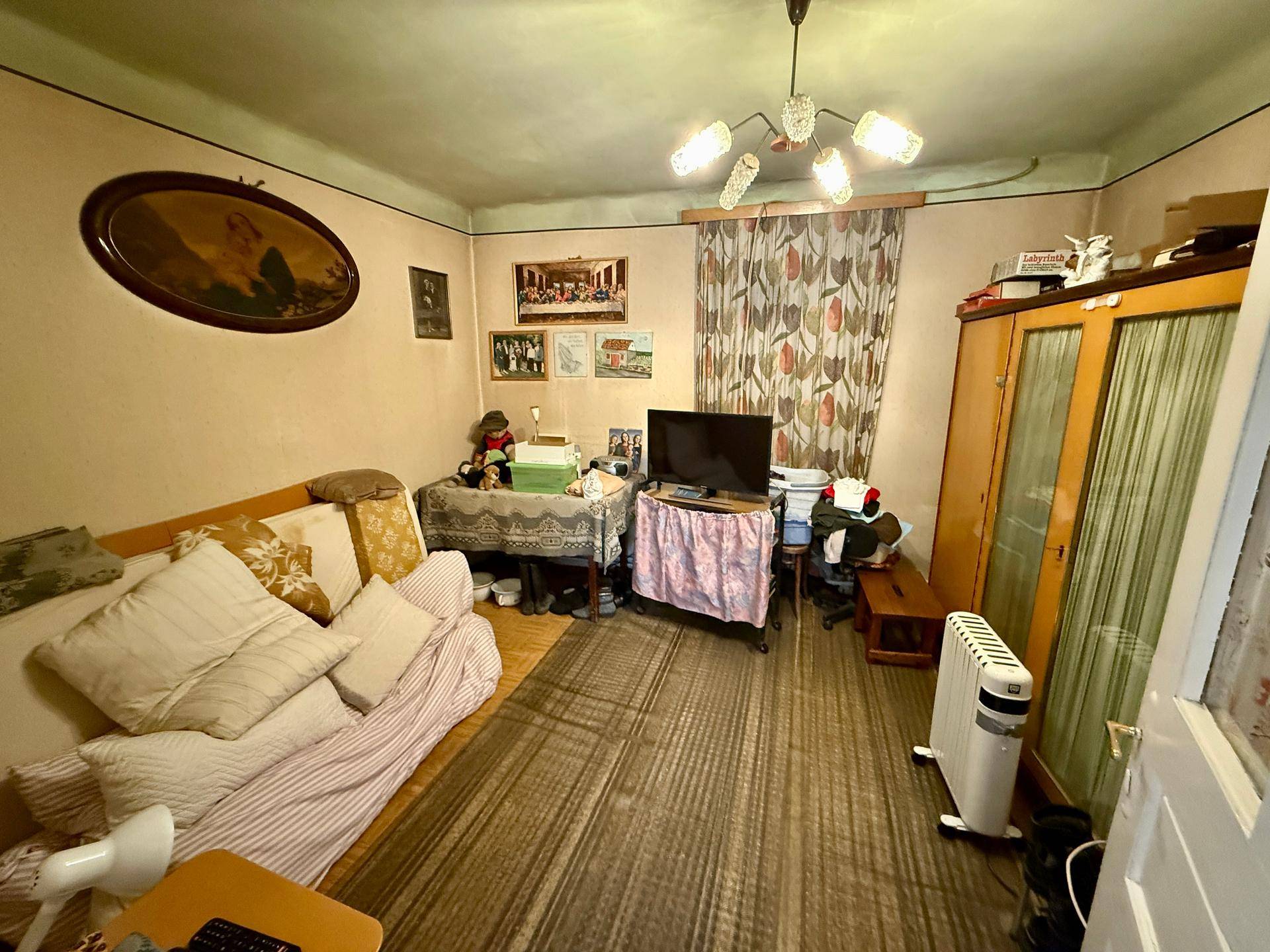 Wohnraum mit Sofa, Fernseher und Kleiderschrank, dekoriert mit traditionellen Elementen.