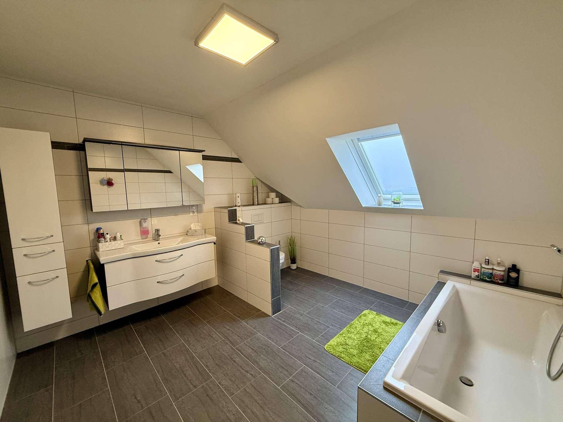 Geräumiges Badezimmer im Dachgeschoss mit Badewanne, Doppelwaschbecken und Dachfenster.