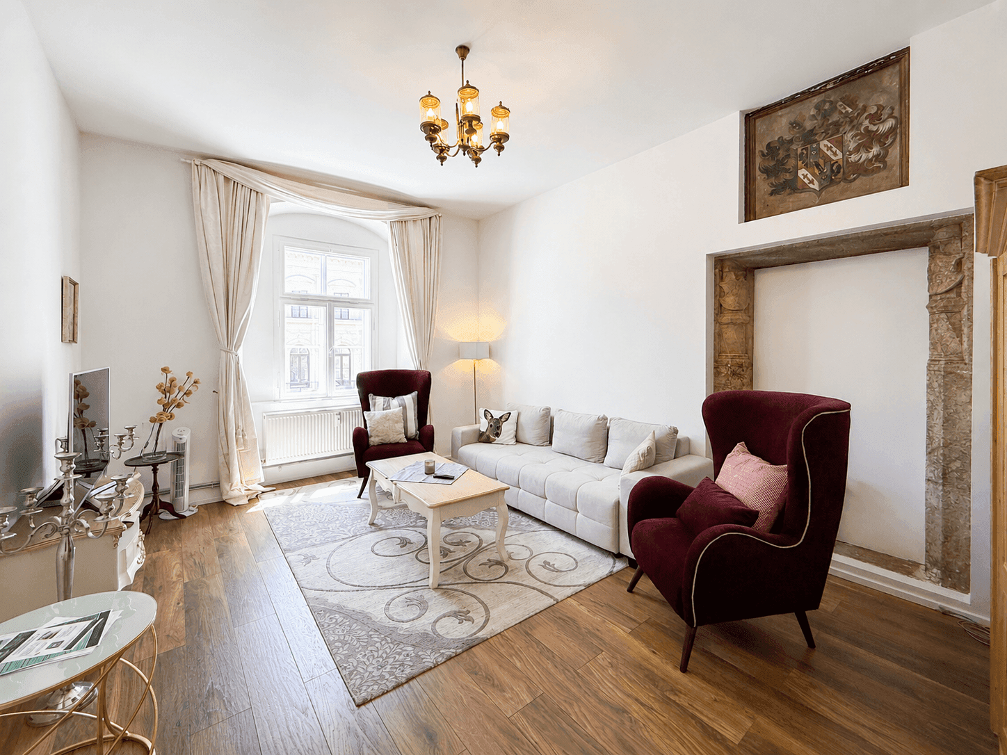 Geräumiges Wohnzimmer mit Holzboden, gemütlichen Sesseln und einem dekorativen Kaminrahmen.