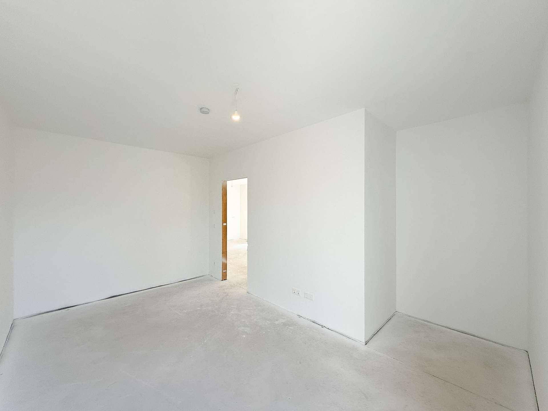 Unmöblierter Raum im Rohbau mit Türöffnung, ideal als zukünftiges Schlaf- oder Arbeitszimmer.