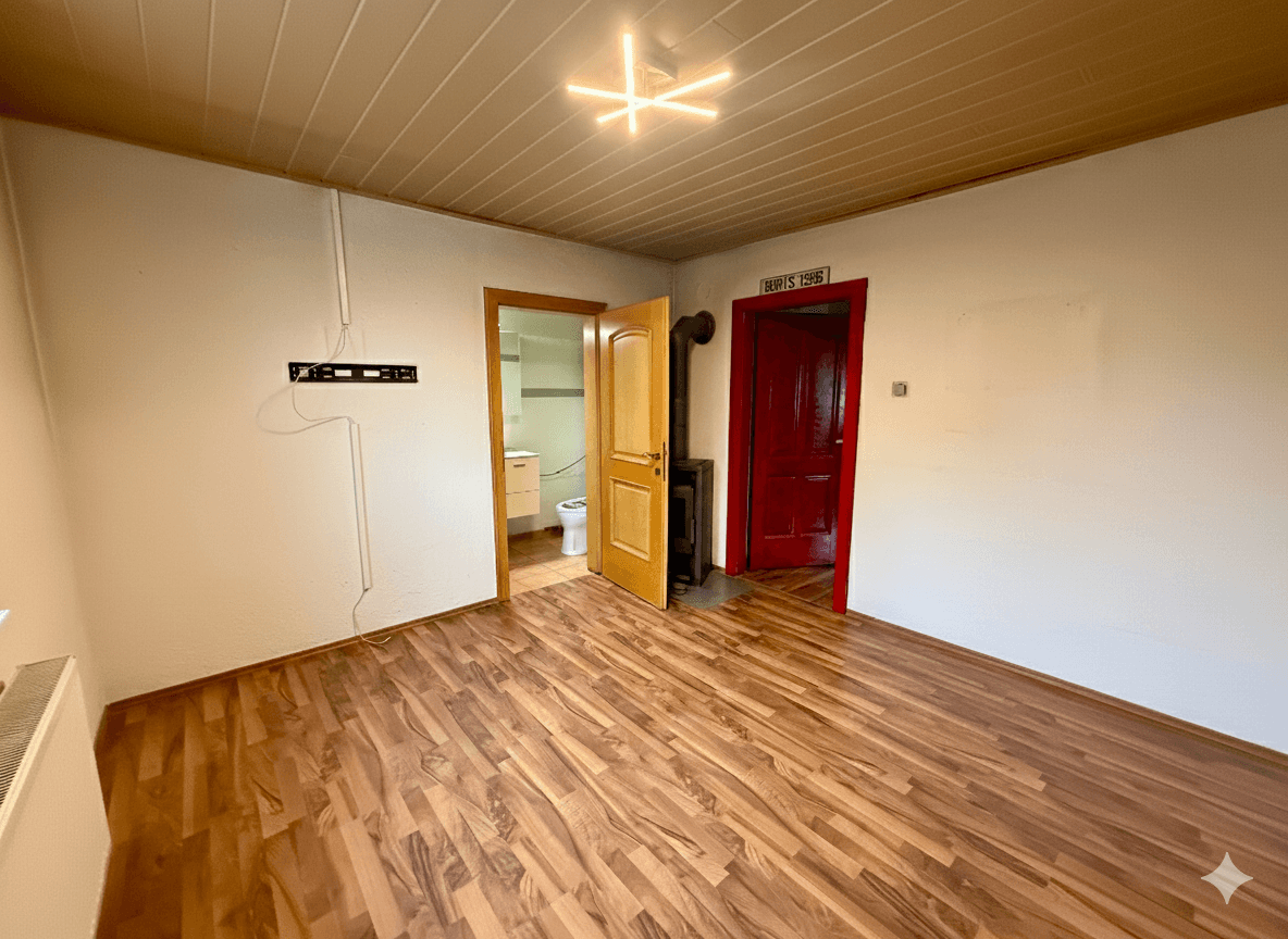 Geräumiges Zimmer mit Holzboden, Holzdecke und einem gemütlichen Holzofen.