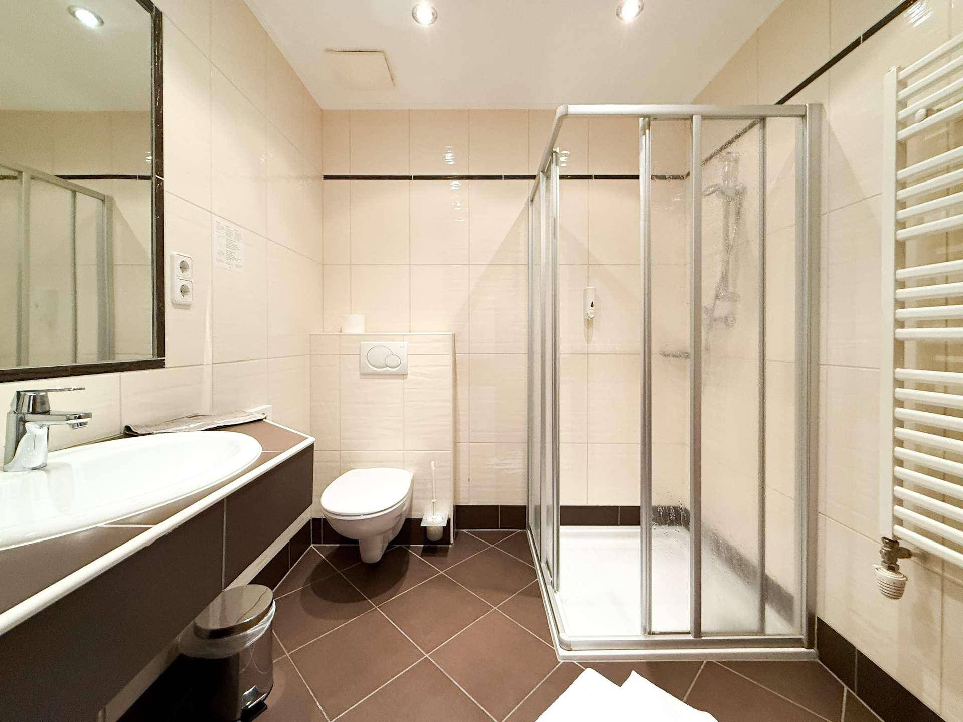 Modernes Badezimmer mit Duschkabine, Wand-WC und Handtuchheizkörper.