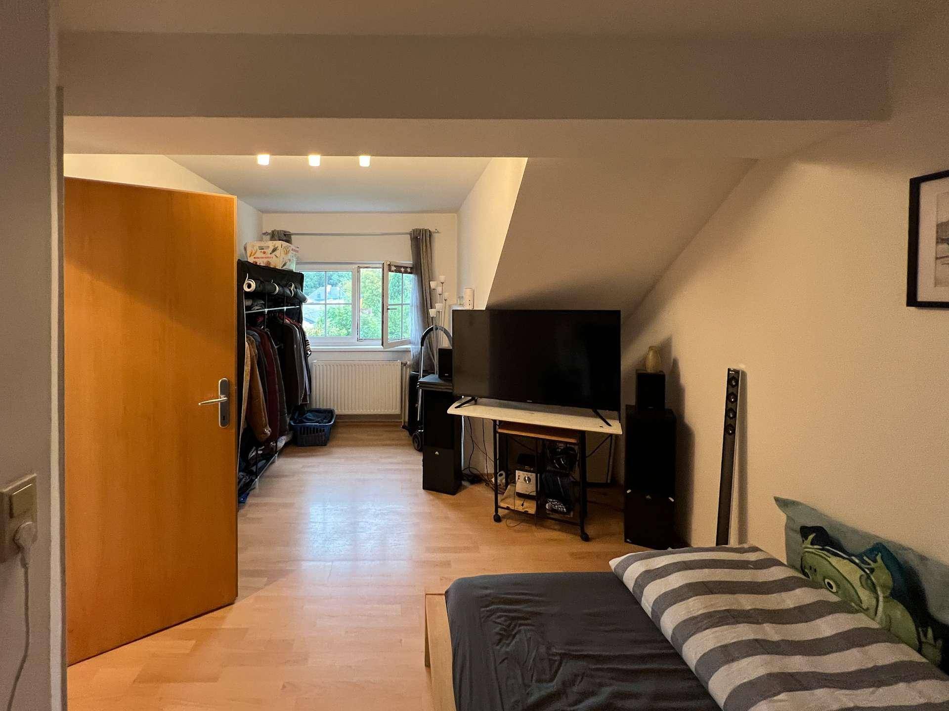 Gemütliches Schlafzimmer im Dachgeschoss mit Fernseher und offenem Kleiderschrank.