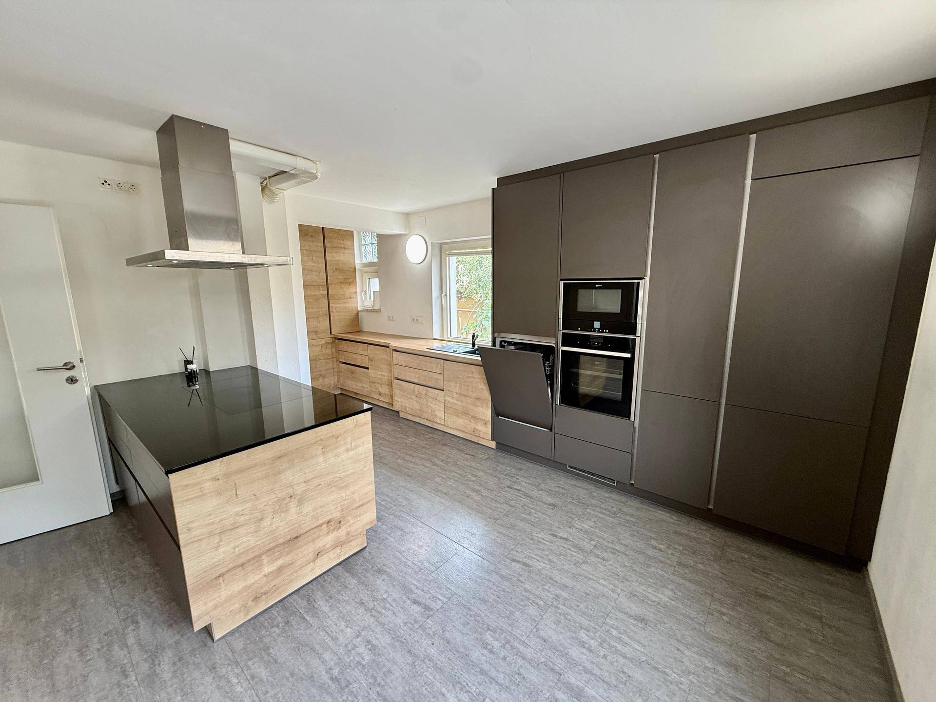Detailansicht der modernen Küche mit dunklen Schränken, Holzdetails und integrierten Geräten.