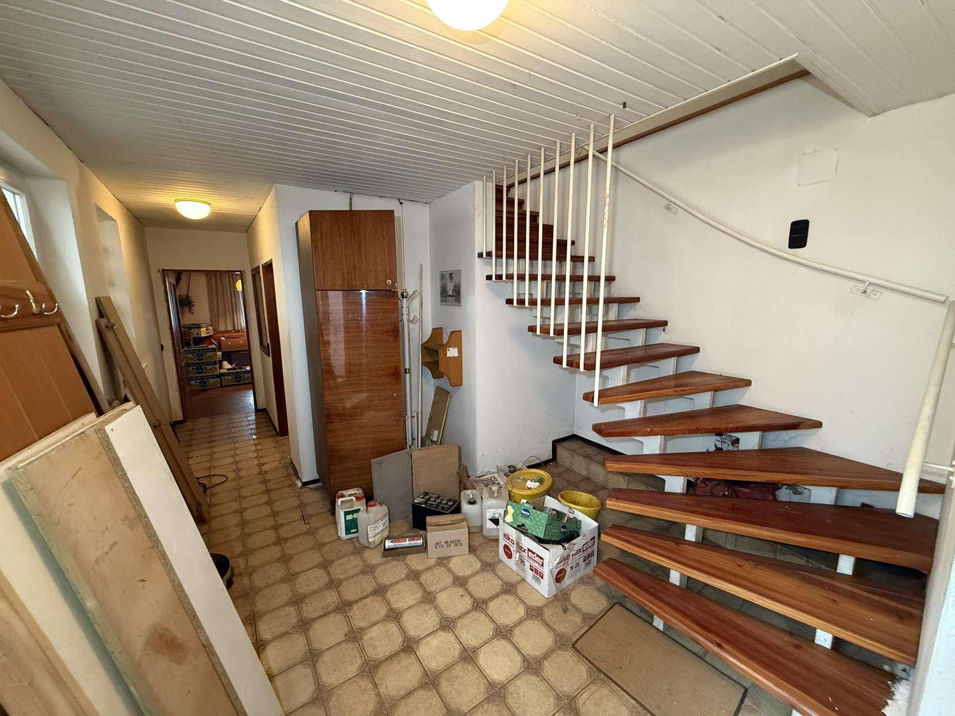 Flur mit Holztreppe und Fliesenboden, der zu den oberen Etagen des Hauses führt.