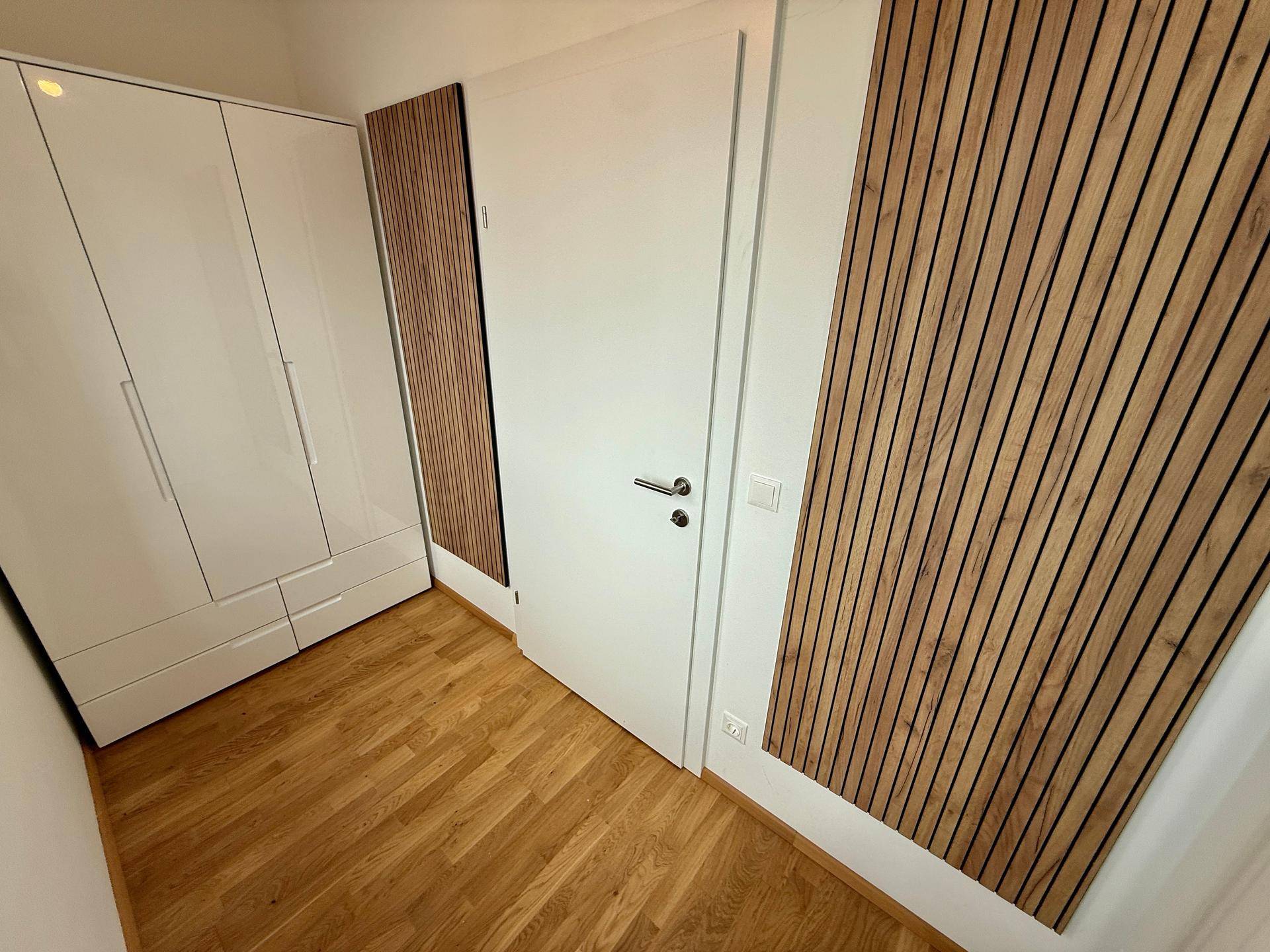 Moderner Flur mit Einbauschränken und dekorativen Holzlamellen an den Wänden.
