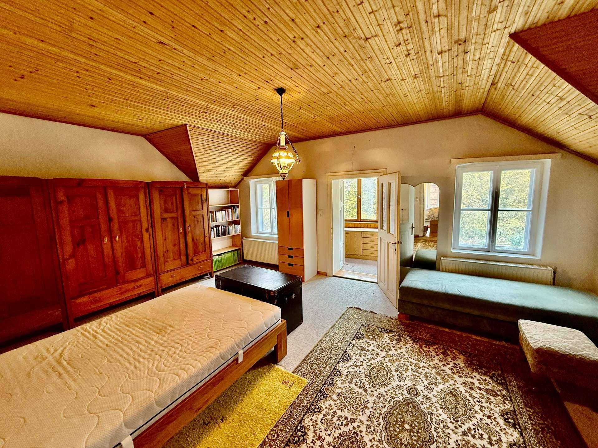 Gemütliches Schlafzimmer mit Holzdecke, Teppich und traditionellen Holzmöbeln.