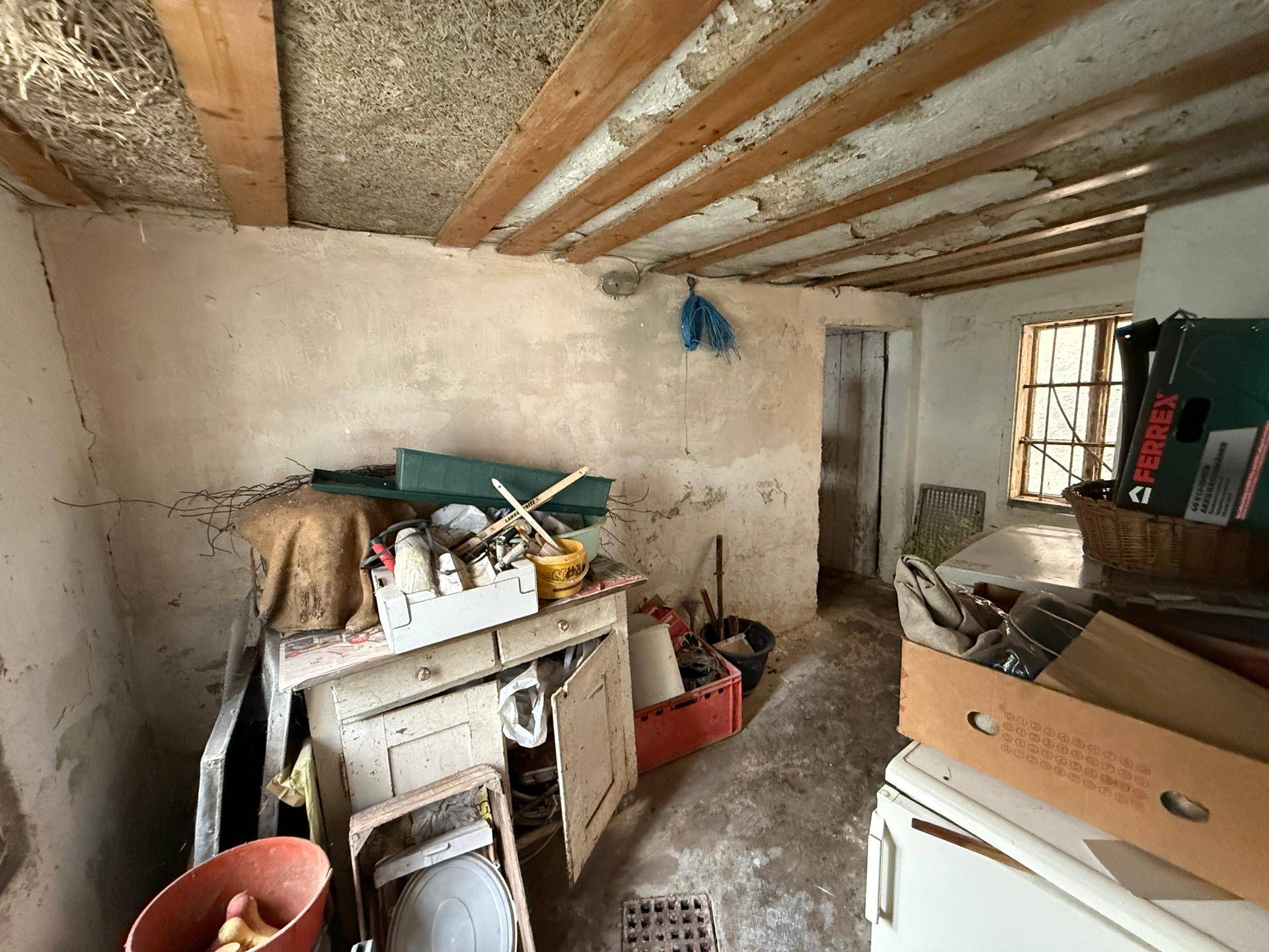 Rustikaler Arbeitsraum mit freiliegenden Holzbalken, rauen Wänden und verschiedenen Werkzeugen.