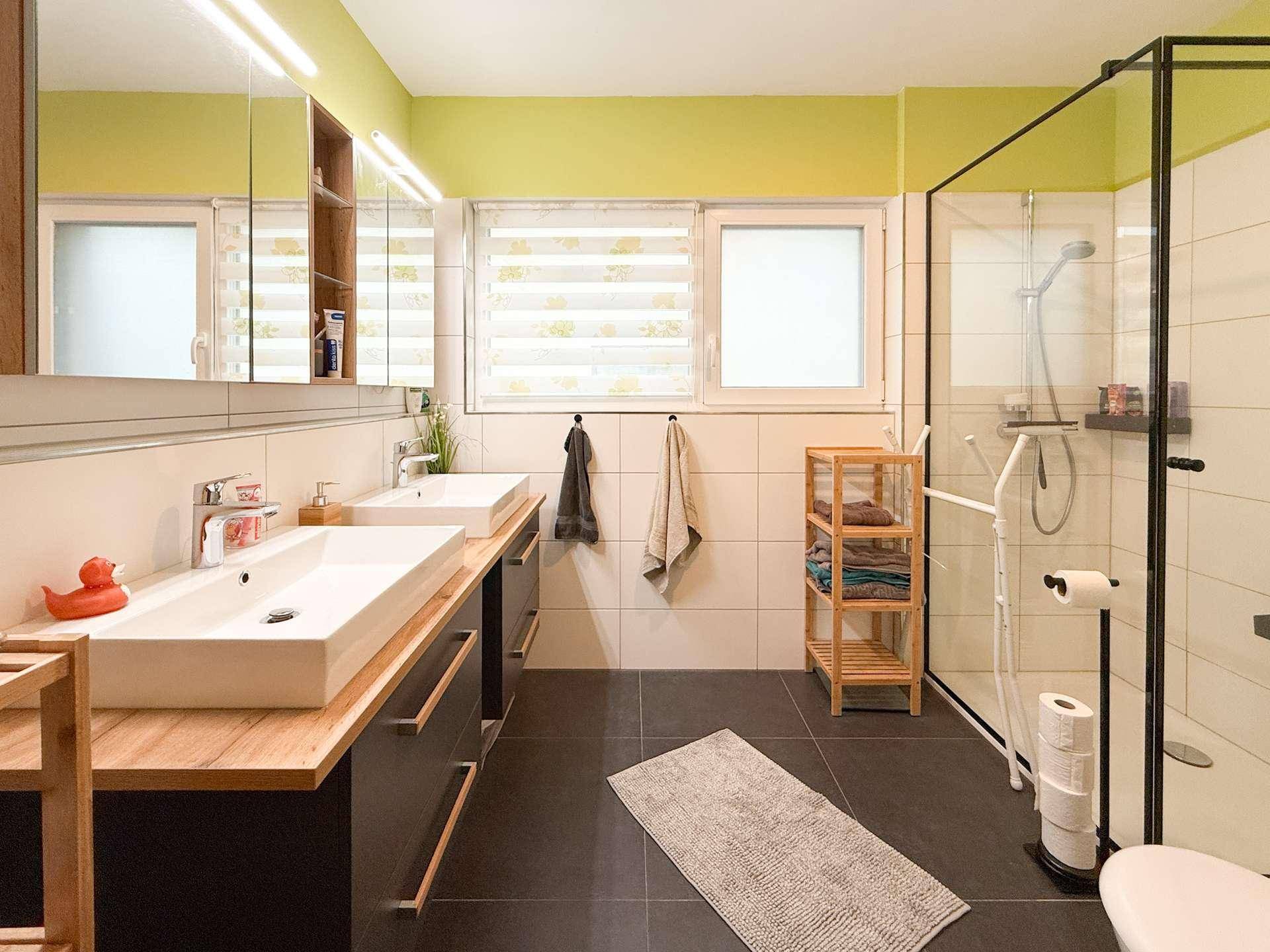 Modernes Badezimmer mit Doppelwaschbecken, großer begehbarer Dusche und Fenster.