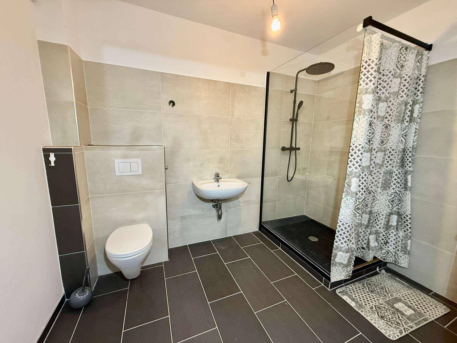 Modernes Badezimmer mit ebenerdiger Dusche, Toilette und Waschbecken.