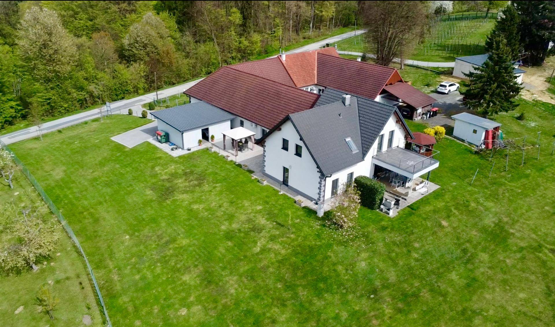 Übersicht des Anwesens mit Wohnhaus, Nebengebäuden und weitläufiger Grünfläche.