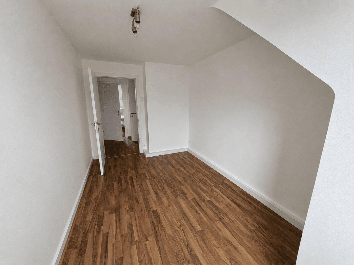 Geräumiges Zimmer mit Laminatboden und Zugang zu weiteren Räumen.