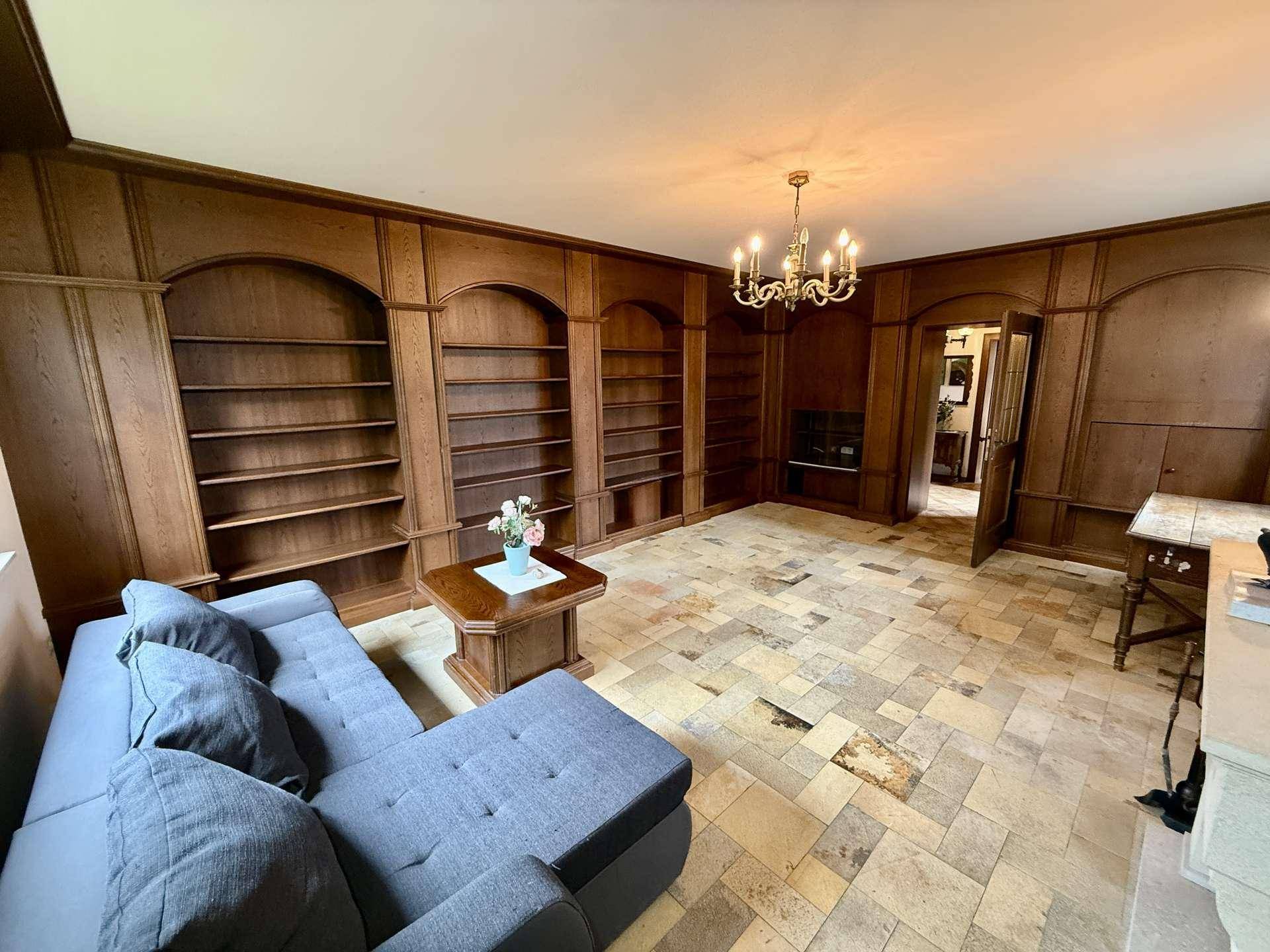 Gemütliches Wohnzimmer mit dunkler Holzvertäfelung, eingebauten Bücherregalen und Fliesenboden.