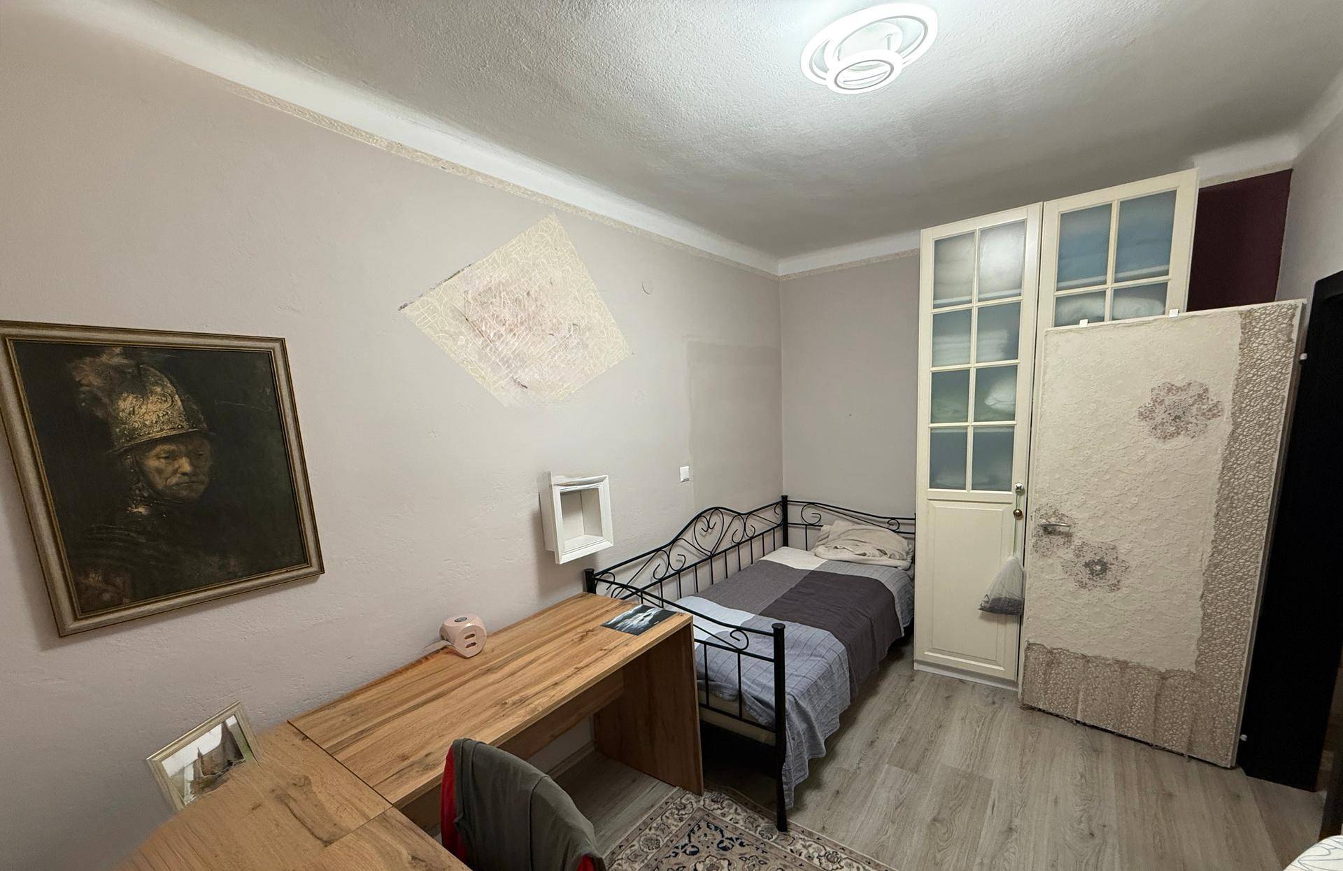 Schlafzimmer mit Einzelbett, Holzschreibtisch und Kleiderschrank, ideal als Kinder- oder Gästezimmer.