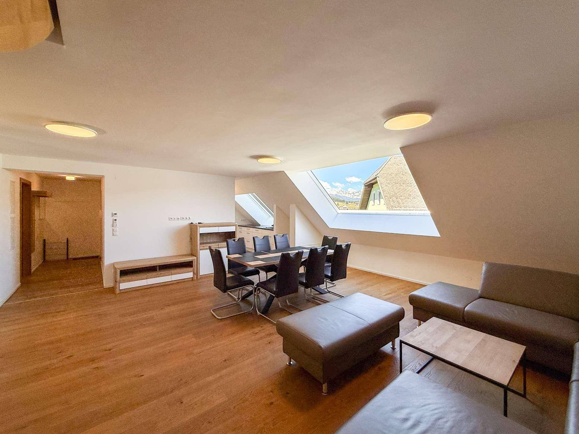 Geräumiger Wohn- und Essbereich mit Holzboden und einem Dachfenster, das einen malerischen Bergblick bietet.