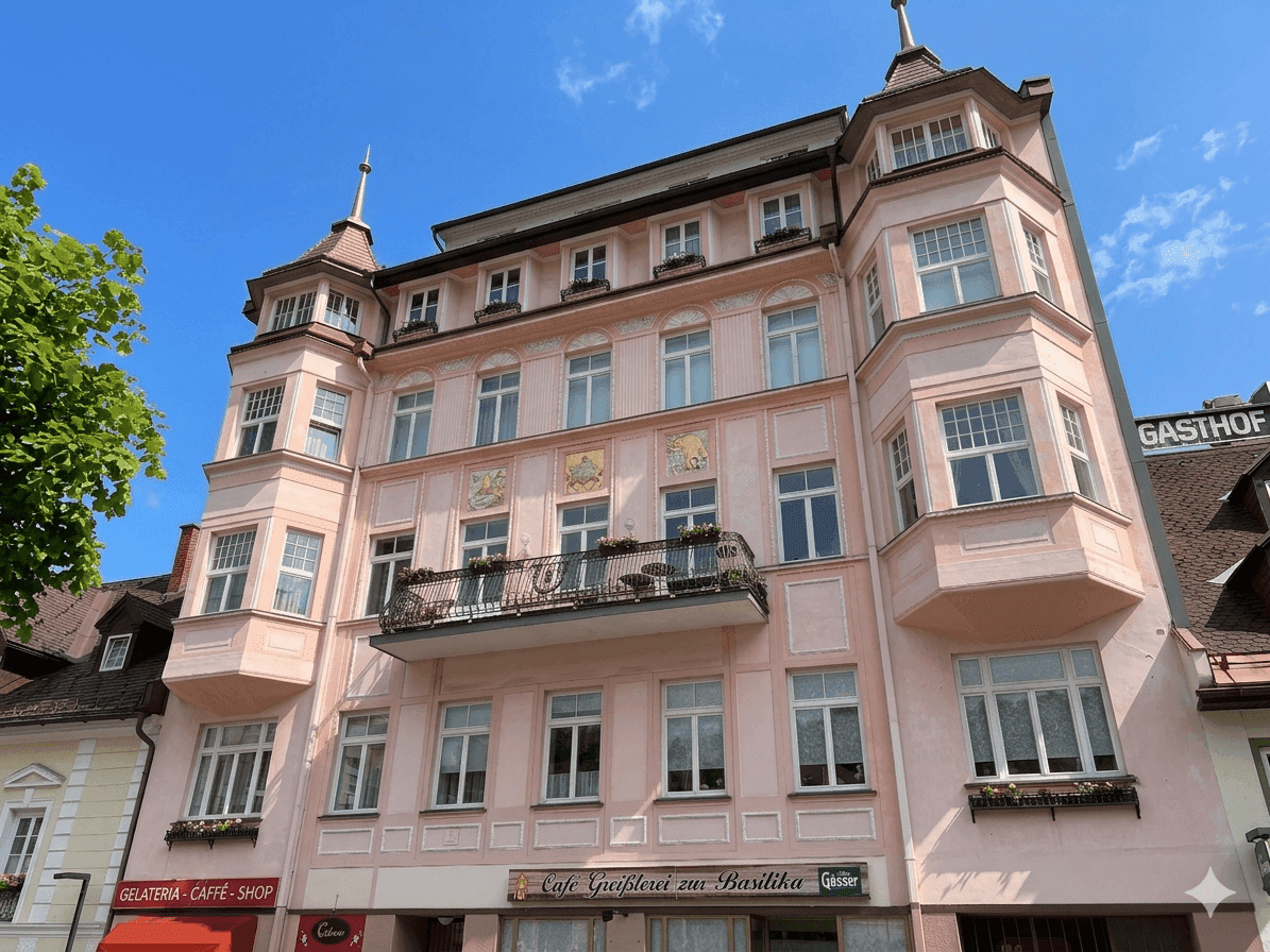 Historisches Gebäude mit rosa Fassade, vielen Fenstern und dekorativen Balkonen in der Stadt.