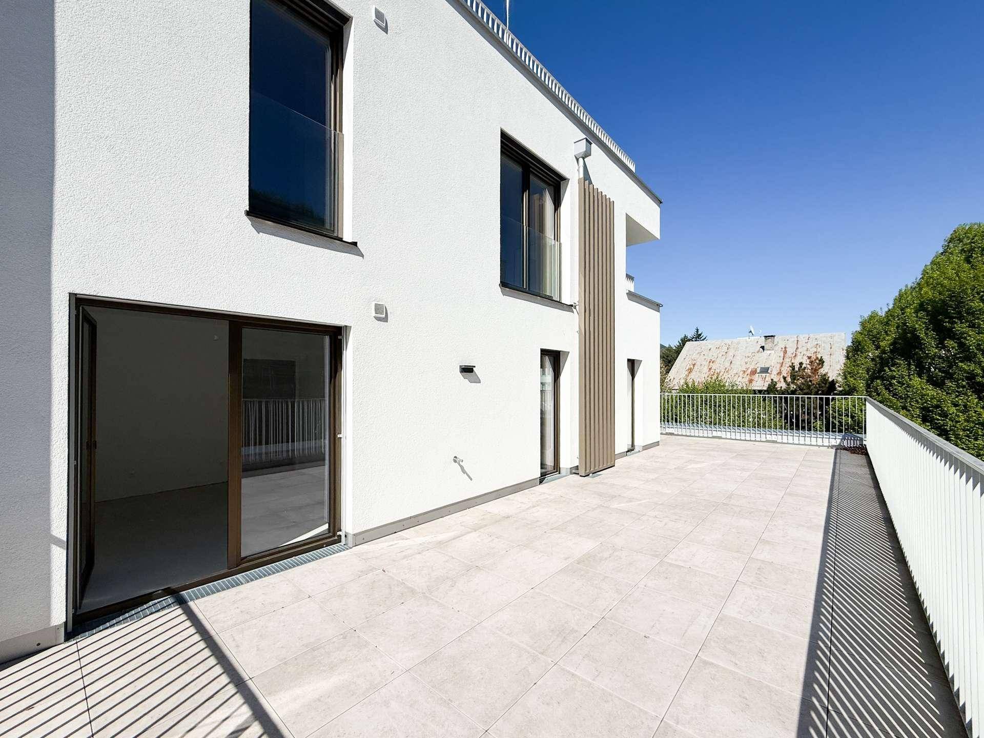Weitläufige, leere Terrasse mit hellen Fliesen und moderner Brüstung, bereit zur Gestaltung.