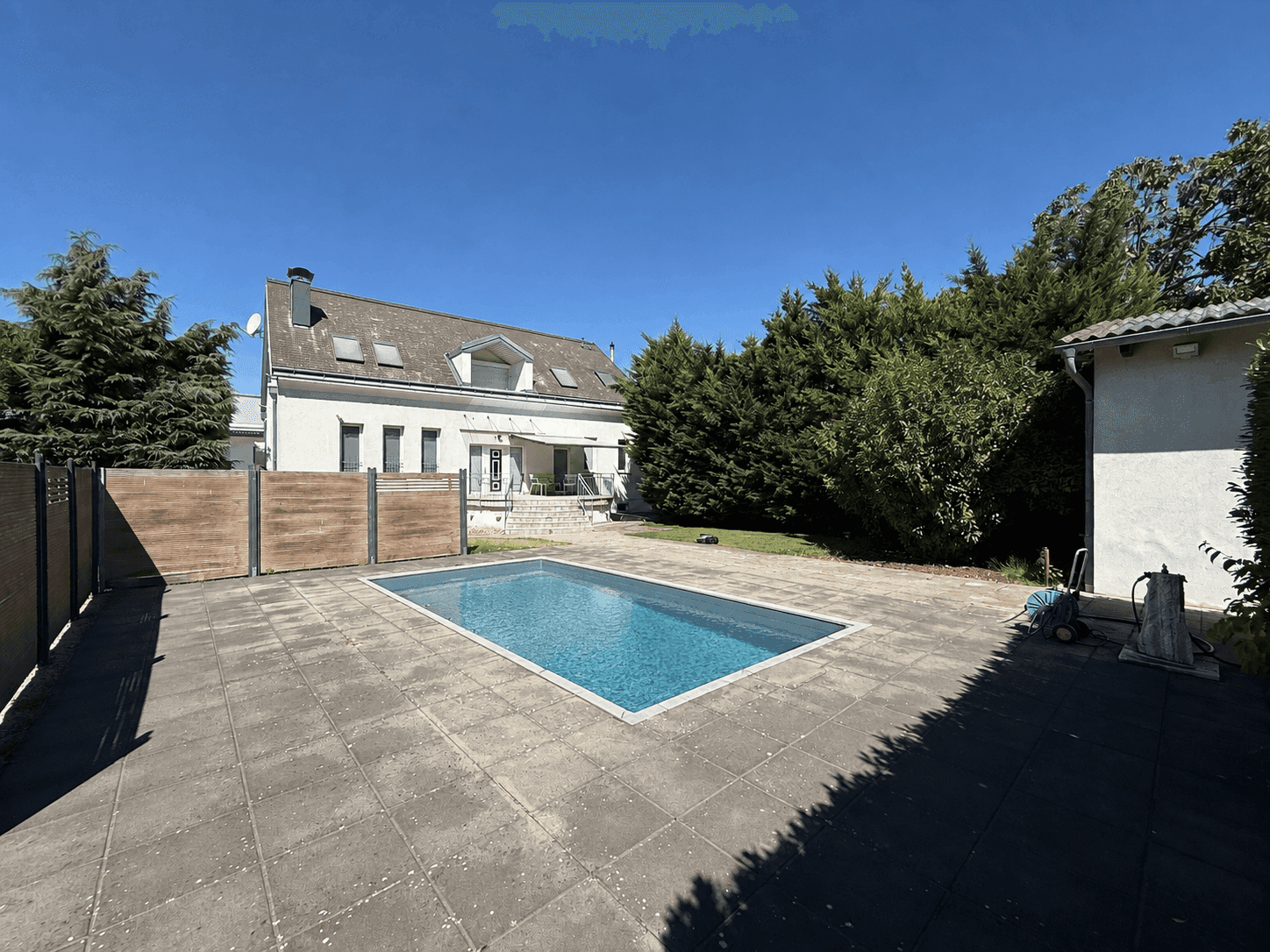 Gepflegter Gartenbereich mit Swimmingpool, großer Terrasse und dem Haus im Hintergrund.