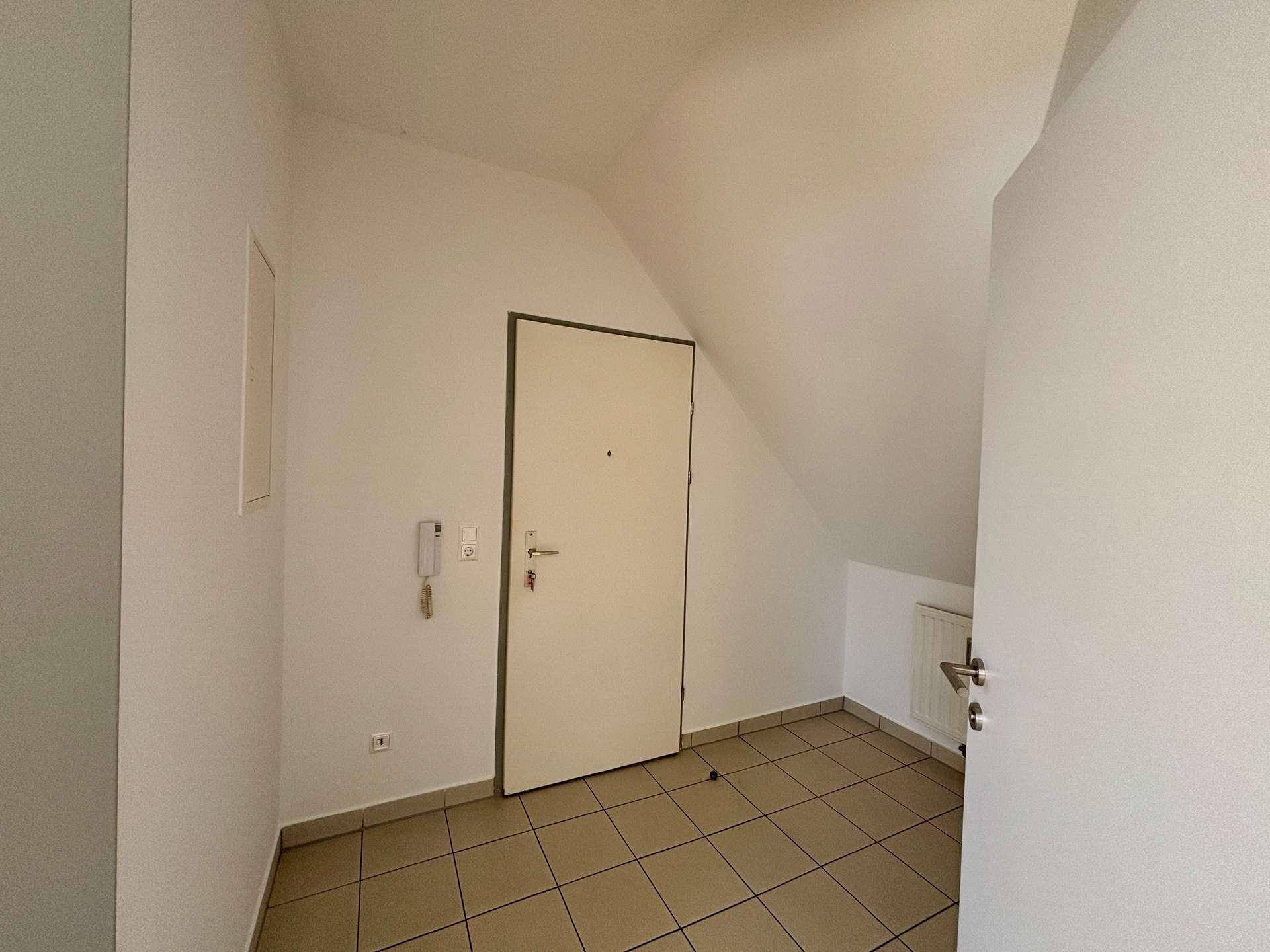Eingangsbereich mit Fliesenboden und einer weißen Eingangstür, die in die Wohnung führt.