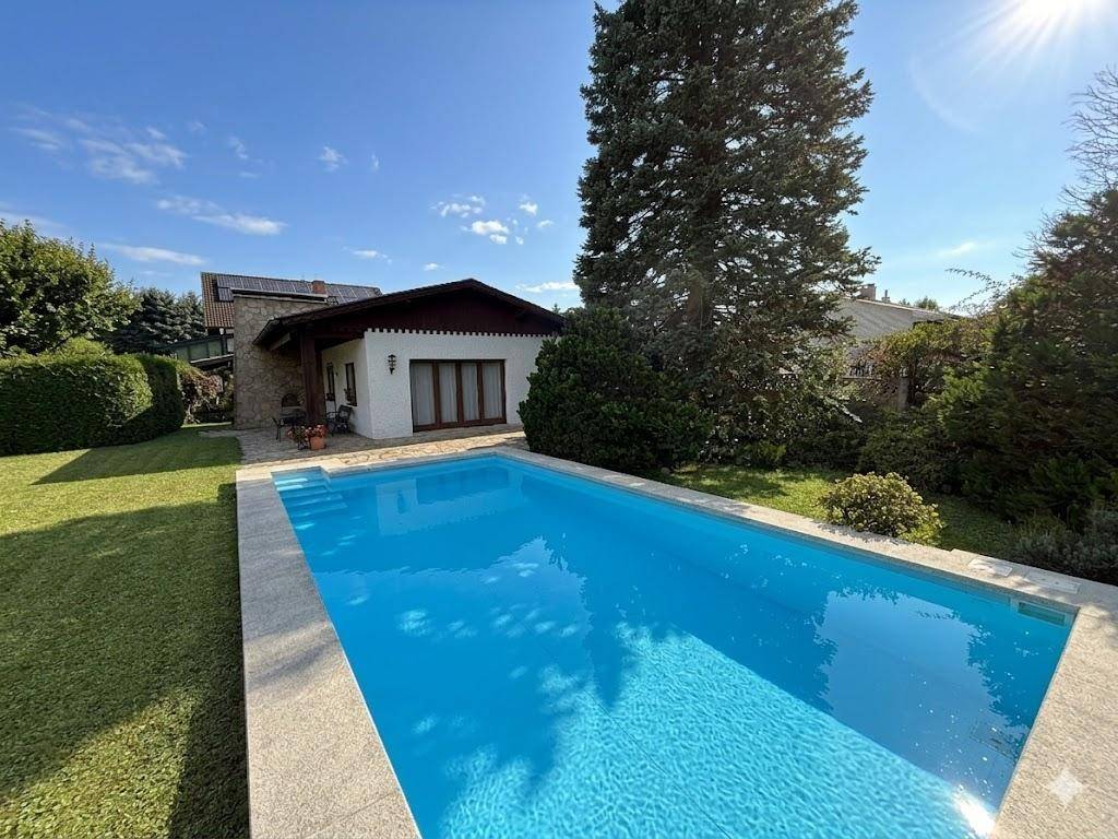 Großer Swimmingpool im Garten mit Blick auf das Haus und die umliegende Natur.