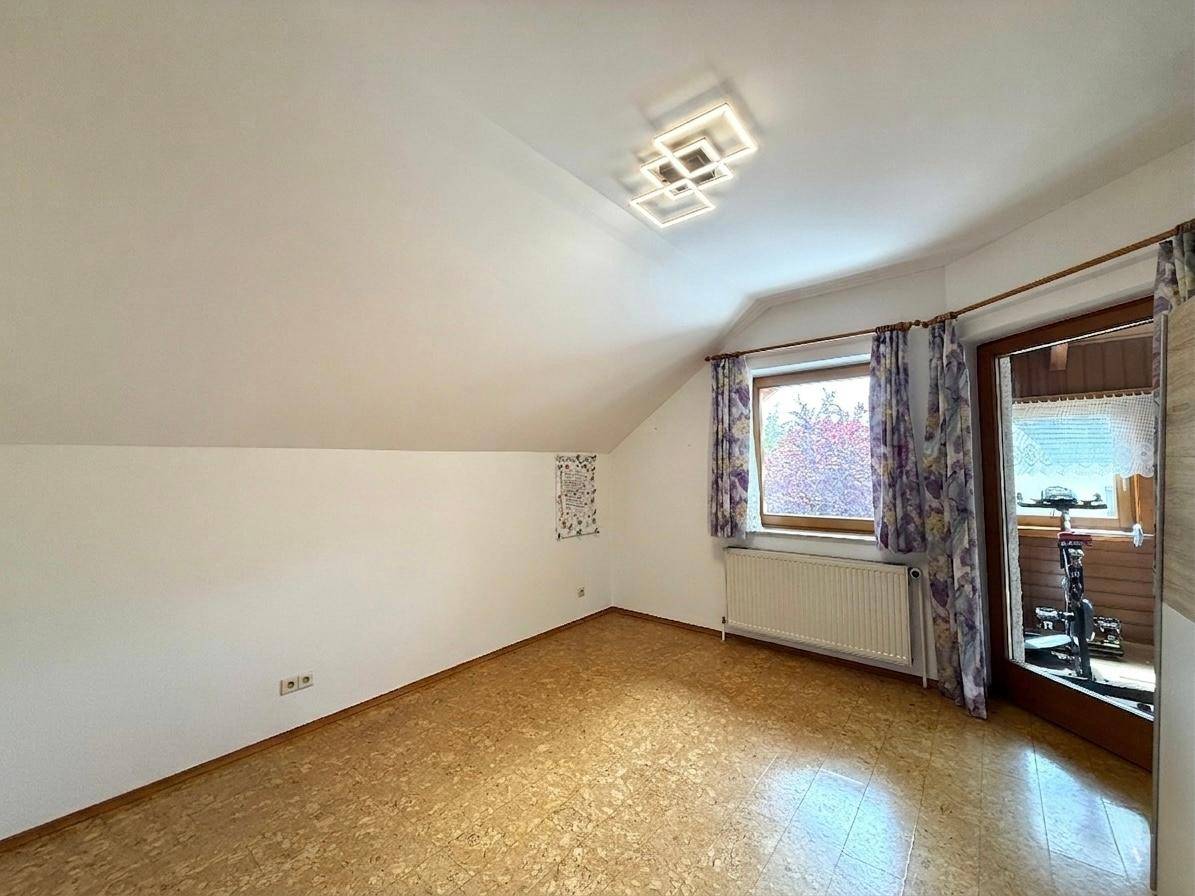 Leeres Schlafzimmer im Dachgeschoss mit Schrägen, Fenster und Korkboden, bereit zur Einrichtung.