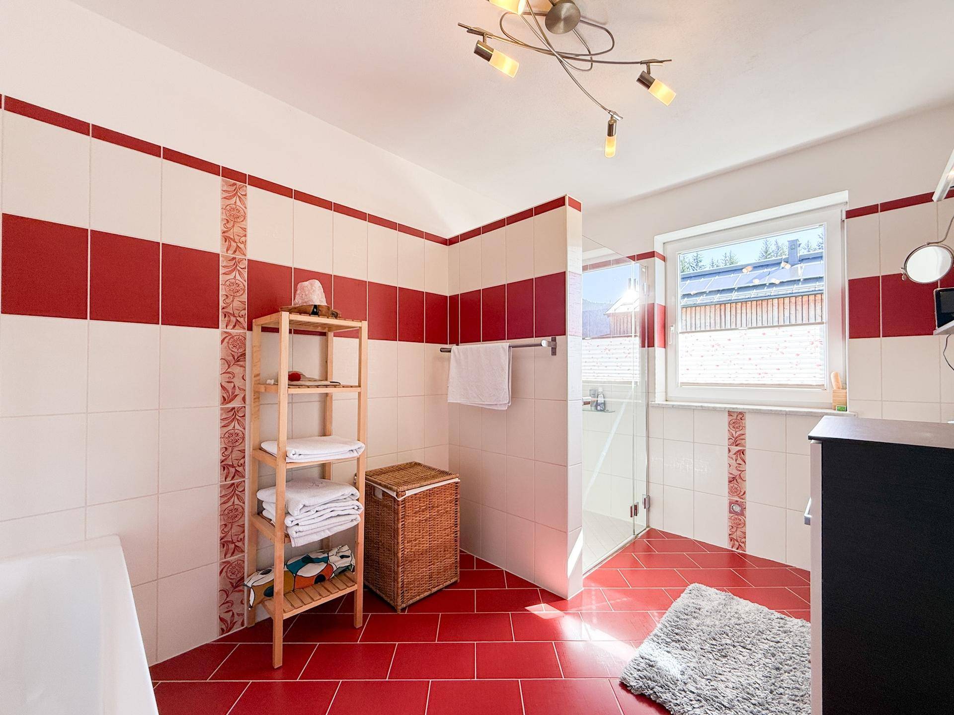 Helles Badezimmer mit Dusche, roten Fliesen und Fenster für natürliches Licht.