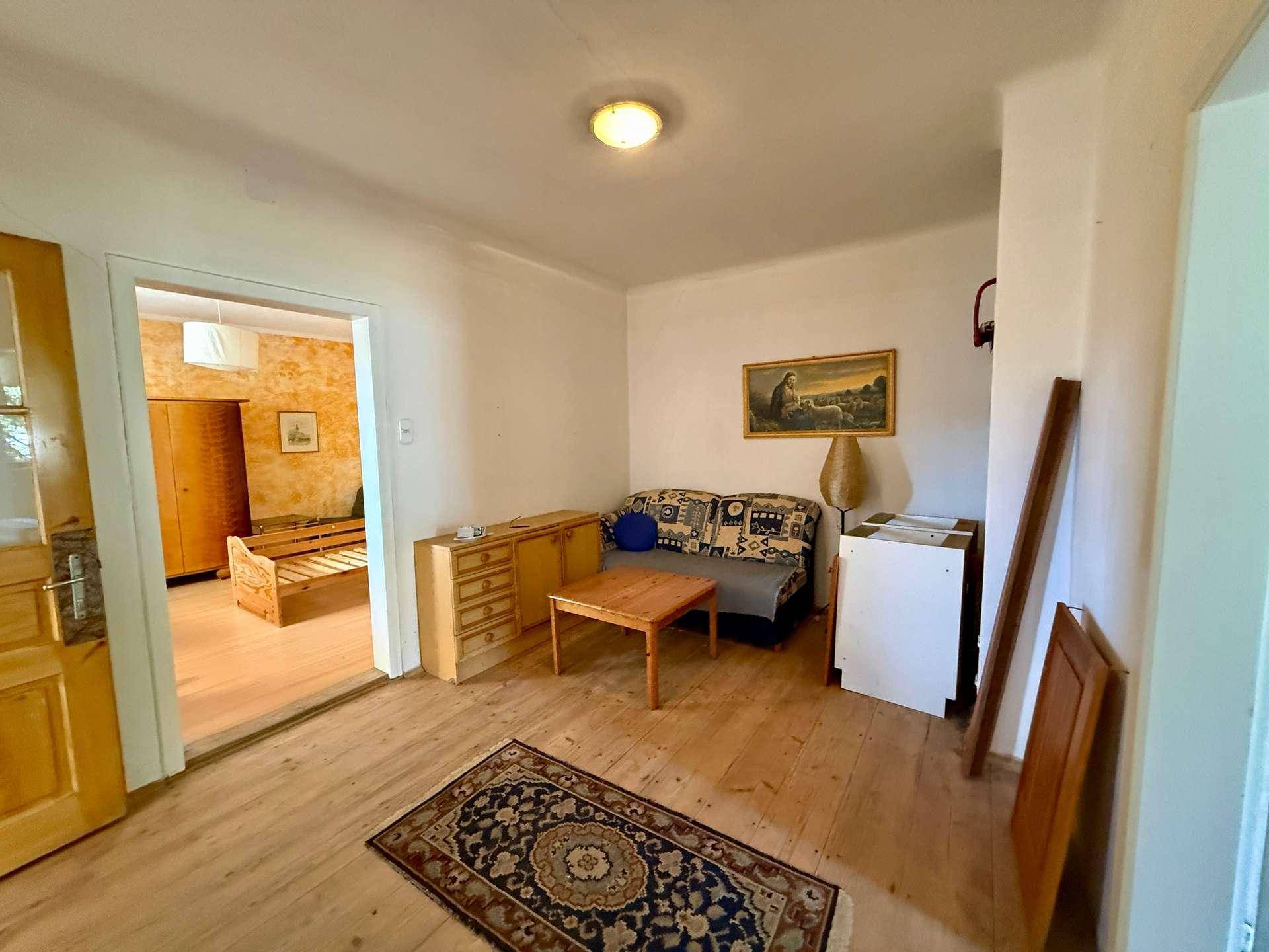 Gemütlicher Wohnbereich mit Holzboden, Sofa und traditionellen Möbeln.