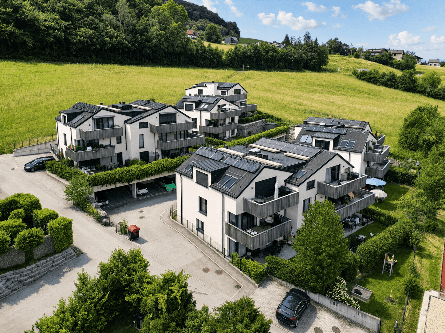 Luftaufnahme einer modernen Wohnsiedlung mit mehreren Gebäuden und viel Grün.