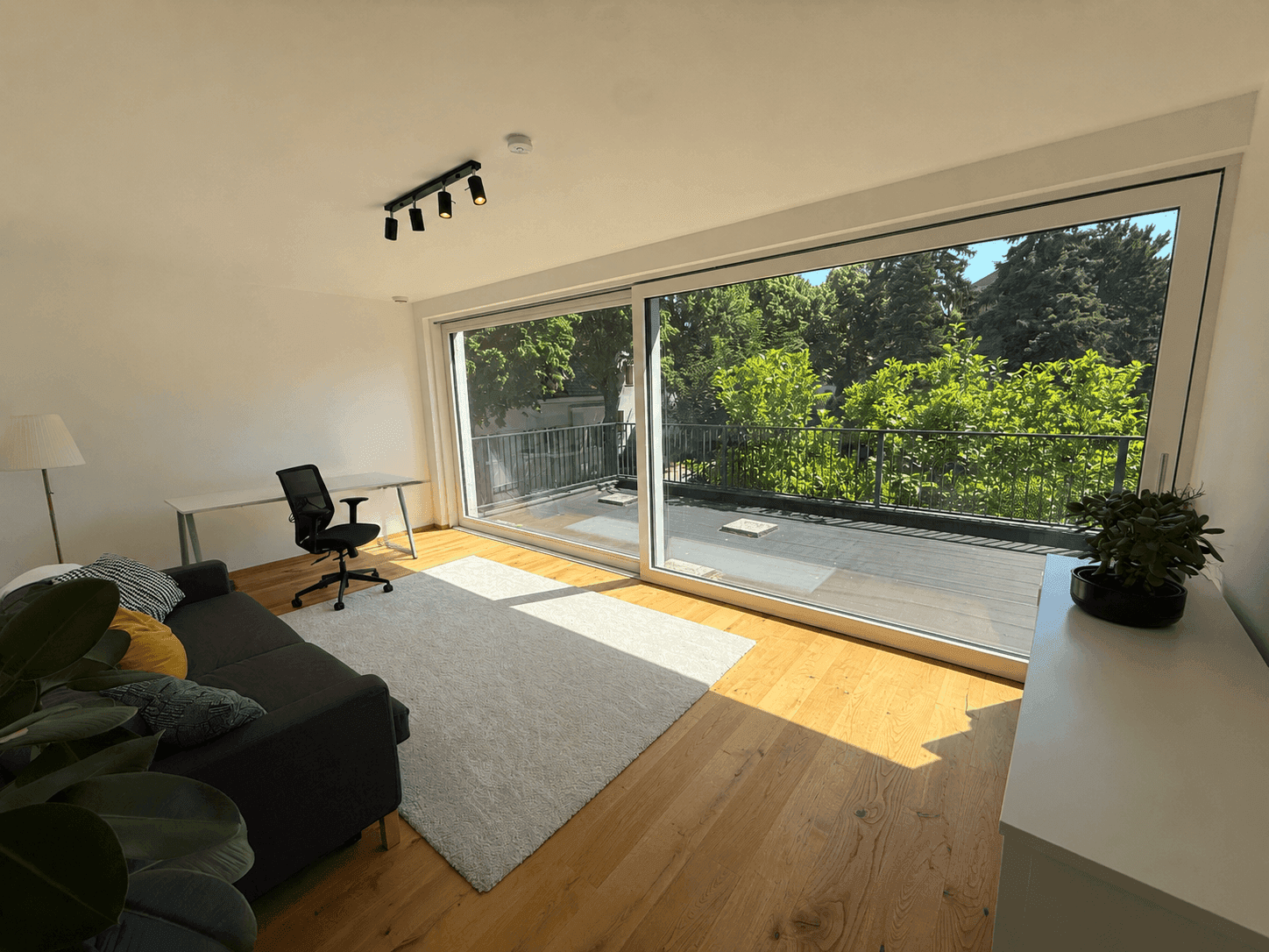 Helles Arbeitszimmer mit großen Schiebetüren, Holzboden und Zugang zur Dachterrasse.