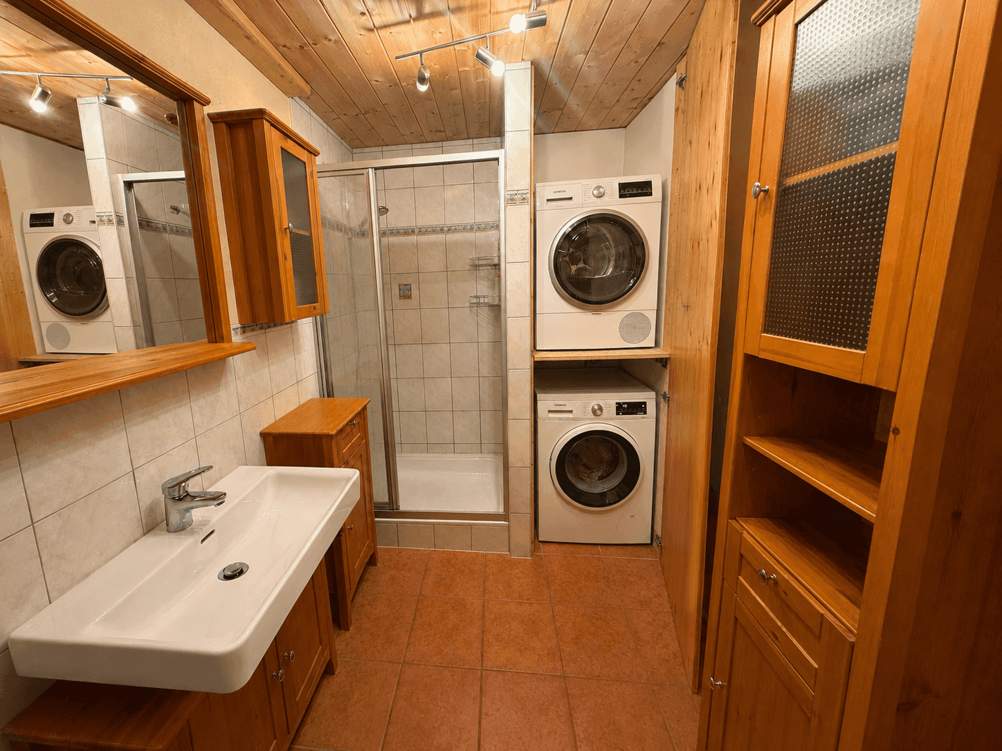 Modernisiertes Badezimmer mit Dusche, Waschbecken und integrierter Waschmaschine und Trockner.