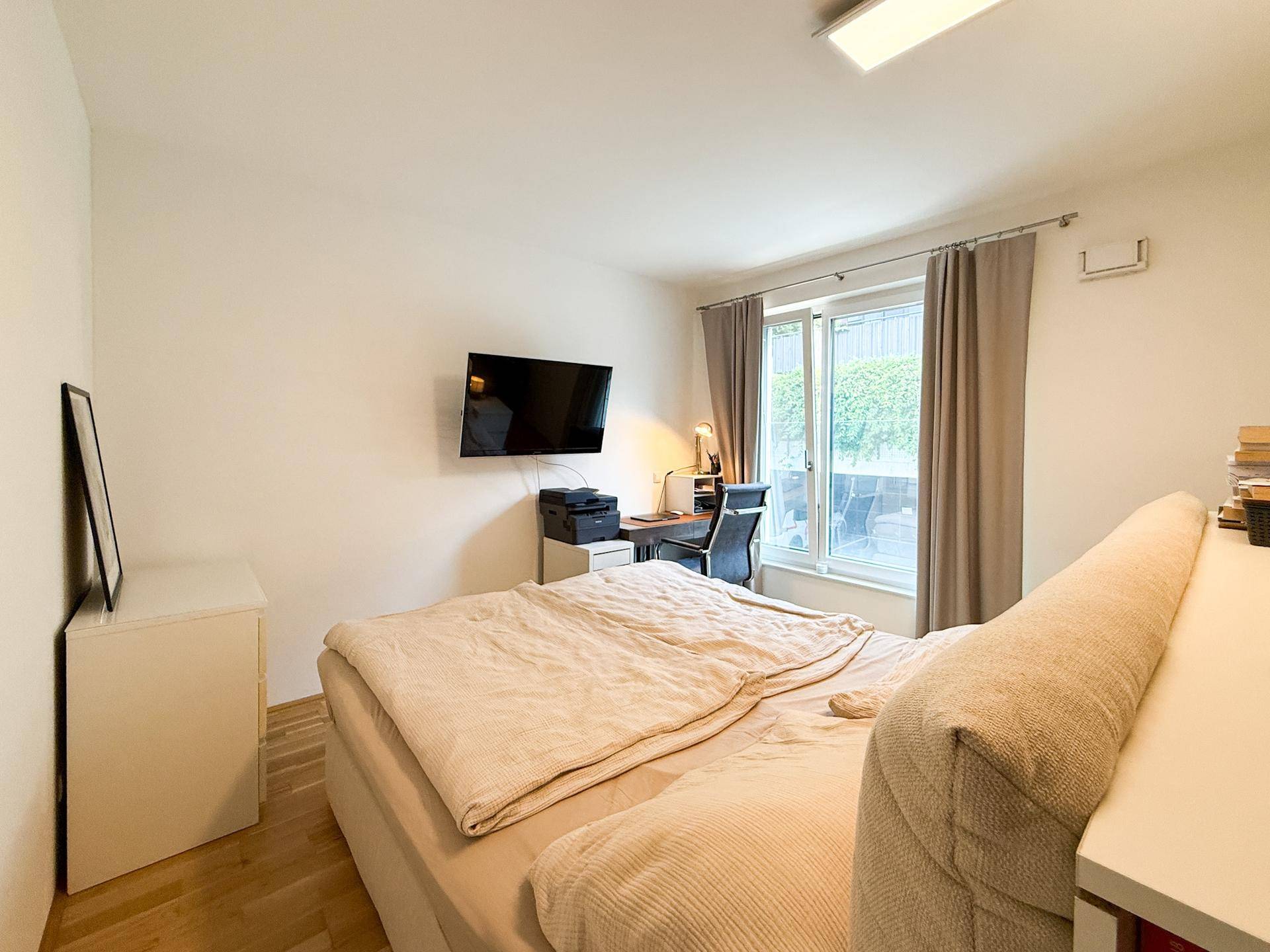 Schlafzimmer mit Doppelbett, Schreibtisch und Fenster mit Blick ins Grüne.