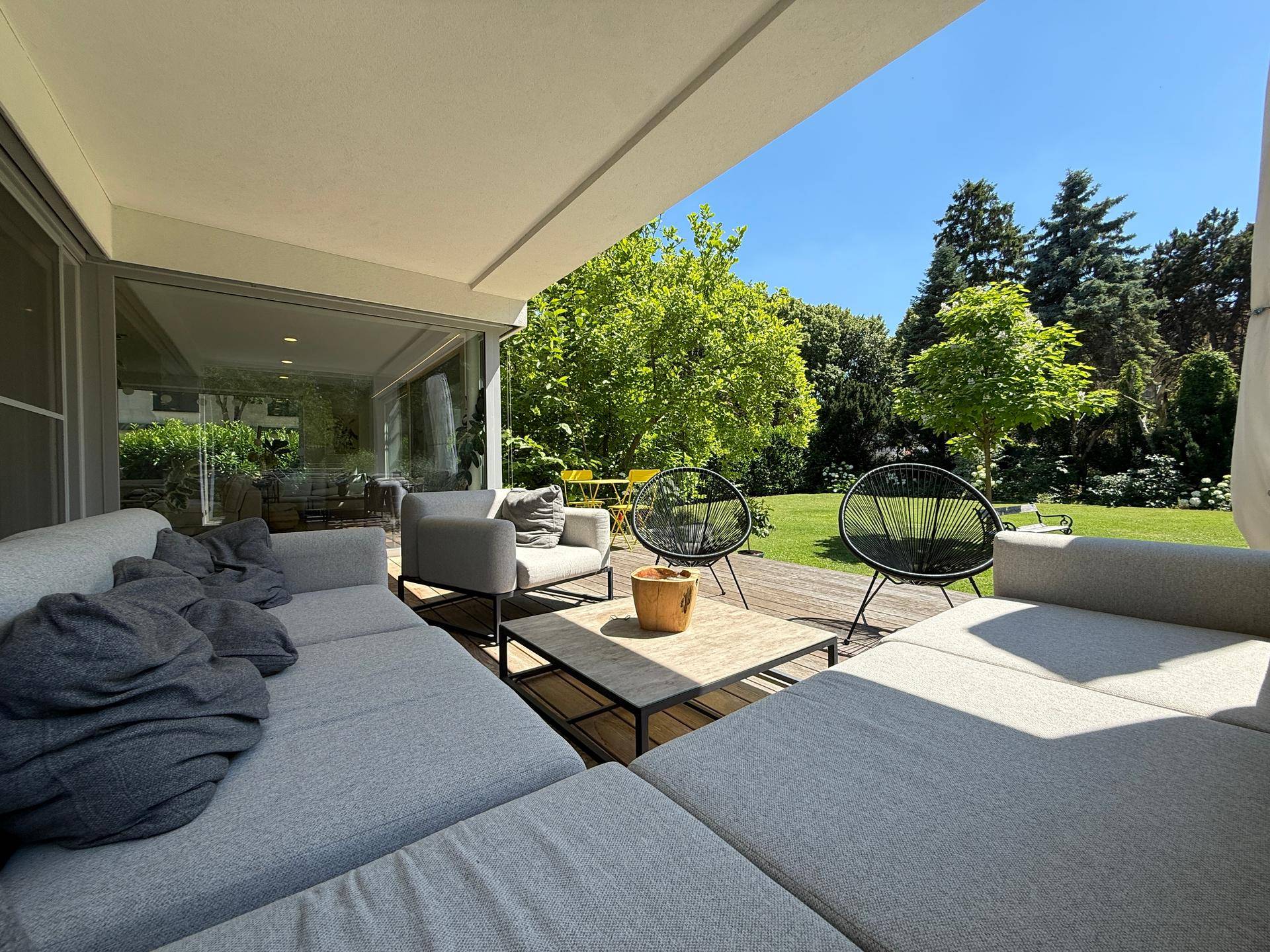 Überdachte Terrasse mit bequemen Loungemöbeln und weitem Blick in den grünen Garten.