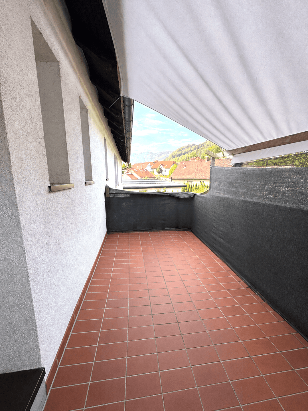 Überdachter Balkon mit Terrakottafliesen und Blick auf die umliegende Landschaft.