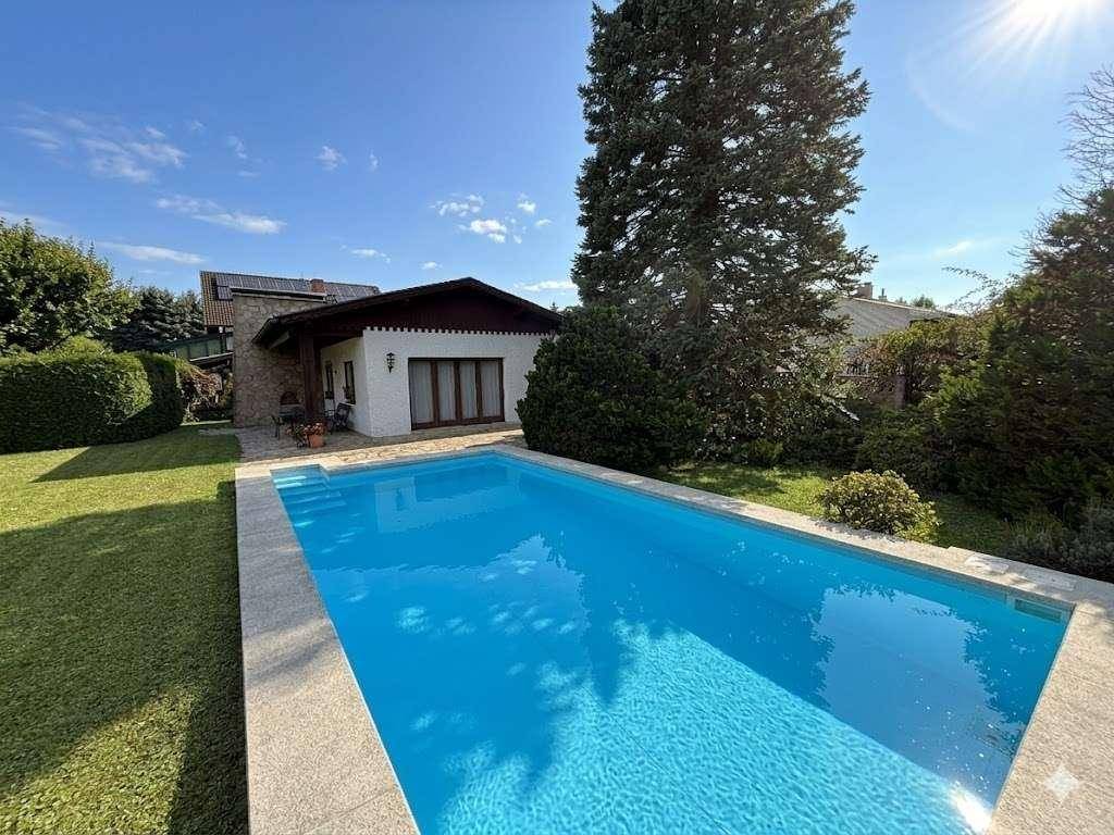 Großer Swimmingpool im Garten mit Blick auf das charmante Einfamilienhaus.