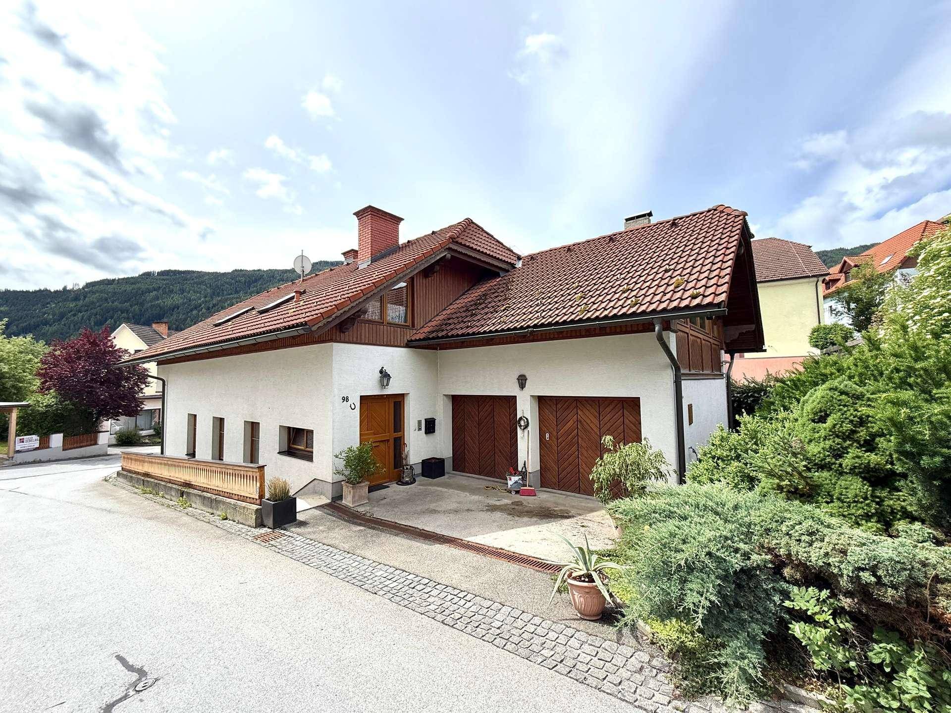 Charmantes Haus mit zwei Garagen und gepflegtem Vorgarten in grüner Umgebung.