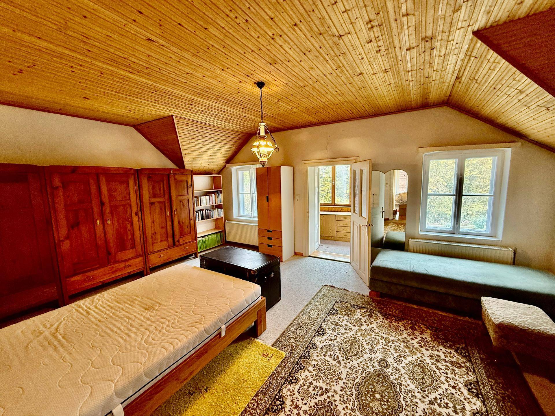 Gemütliches Schlafzimmer mit Holzdecke, Teppichboden und traditionellen Möbeln.