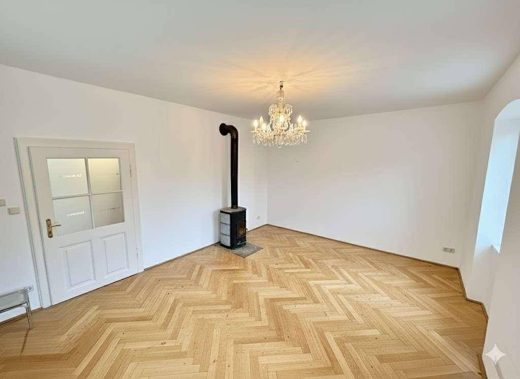 Heller Wohnraum mit Fischgrätparkett und einem gemütlichen Holzofen.