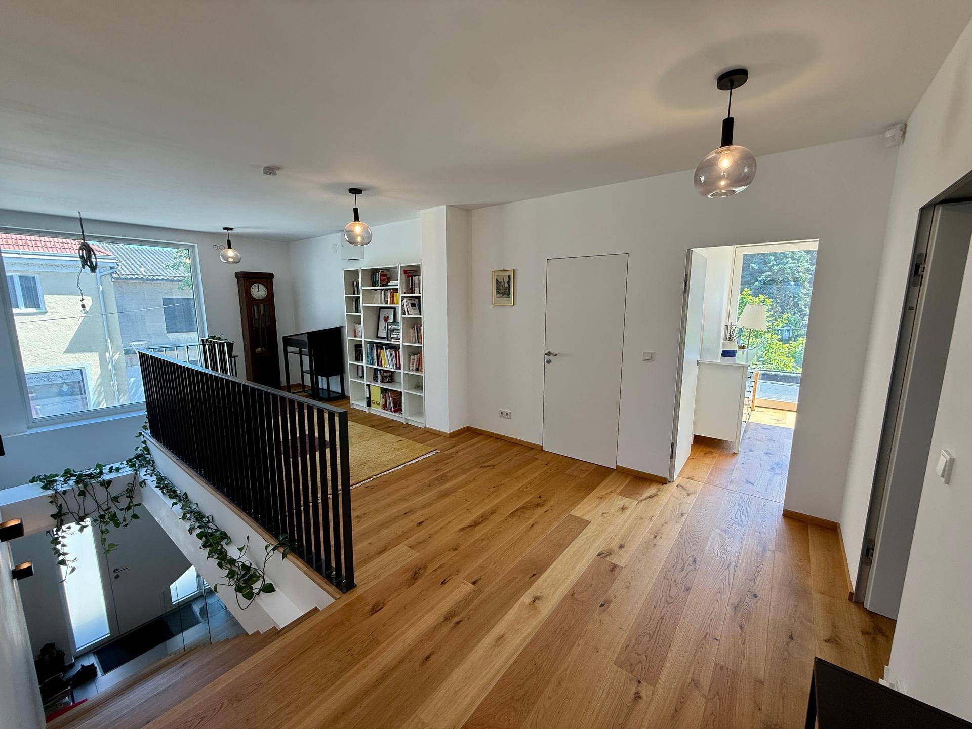 Offener Flur im Obergeschoss mit Holzboden, Bücherregal und Blick in den unteren Bereich.