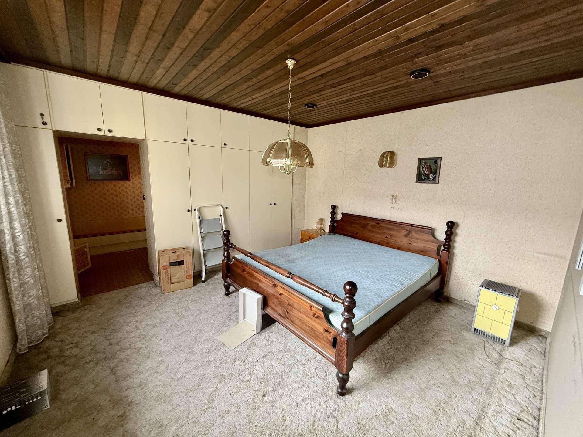 Schlafzimmer im Vintage-Stil mit Holzdecke, Teppichboden und Einbauschränken, die viel Stauraum bieten.