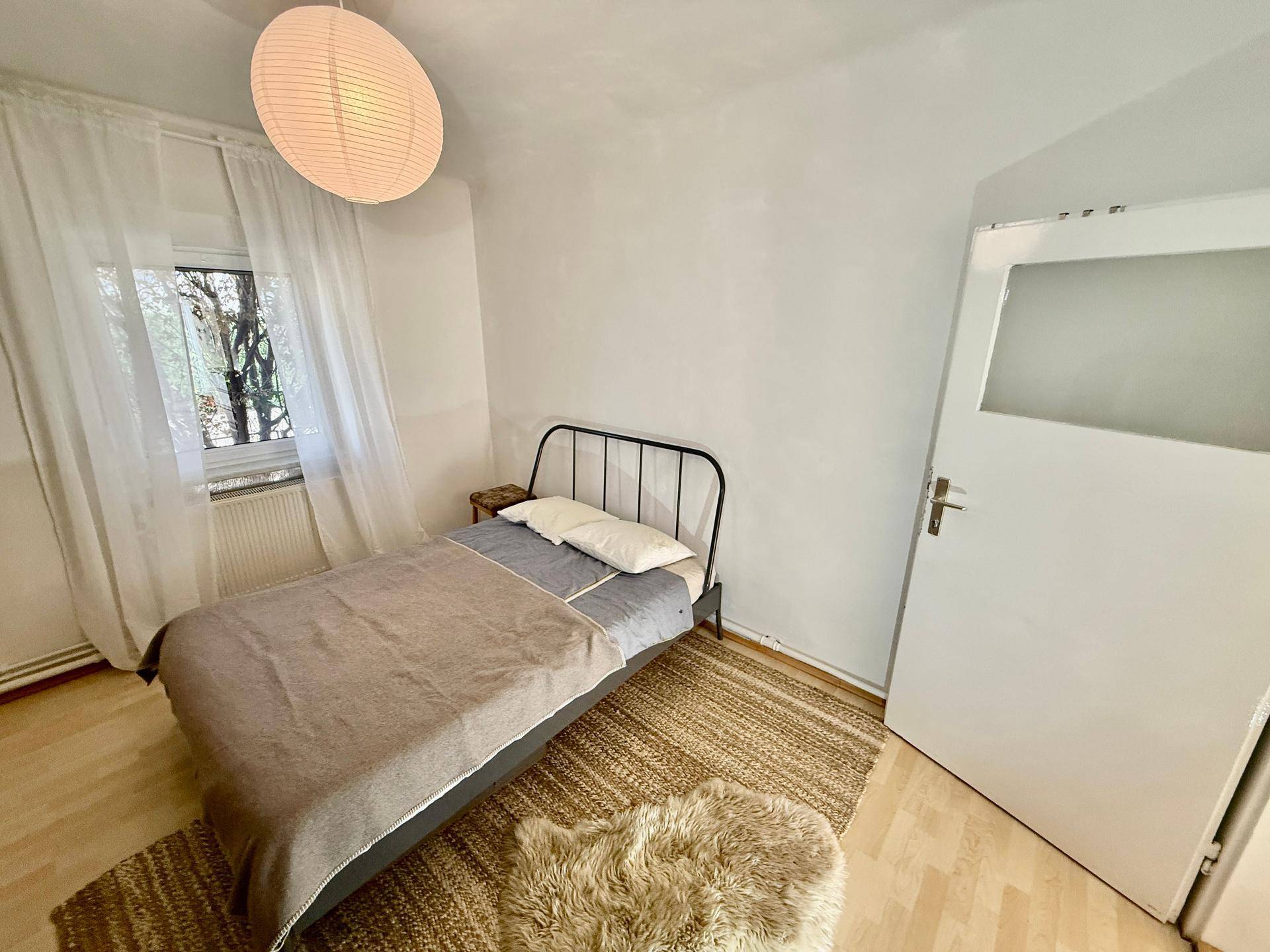 Gemütliches Schlafzimmer mit Einzelbett, Holzboden und einem Fenster für natürliches Licht.