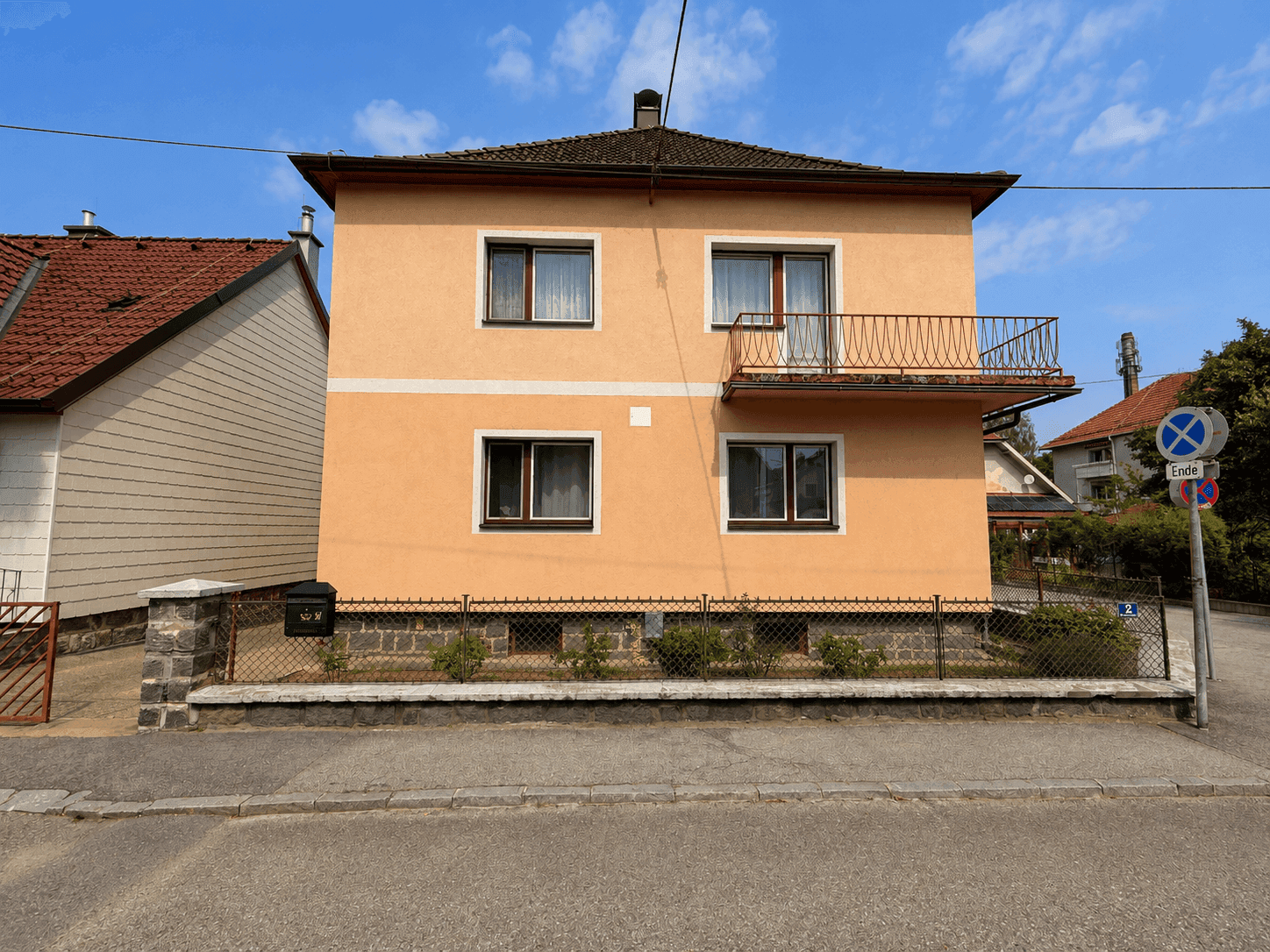 Vorderansicht des Einfamilienhauses mit Balkon und gepflegtem Vorgarten.