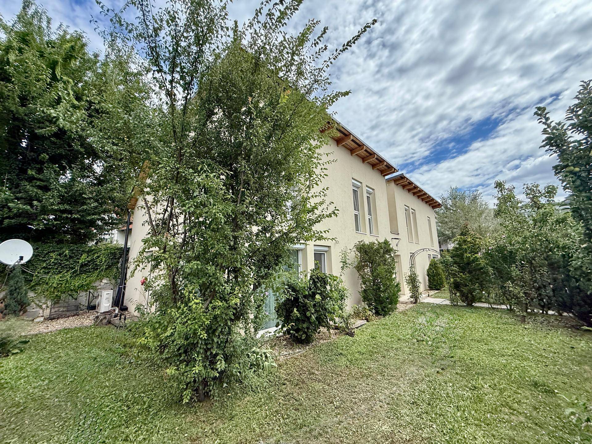 Ansicht des Hauses von der Seite mit gepflegtem Garten und Bäumen.