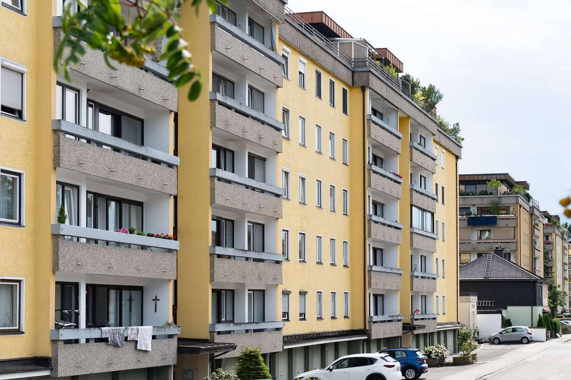 Mehrfamilienhaus mit gelber Fassade und zahlreichen Balkonen in städtischer Umgebung.